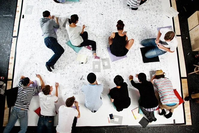Top-down view of people gathered on and engaging directly with the floor-scale artwork installation.