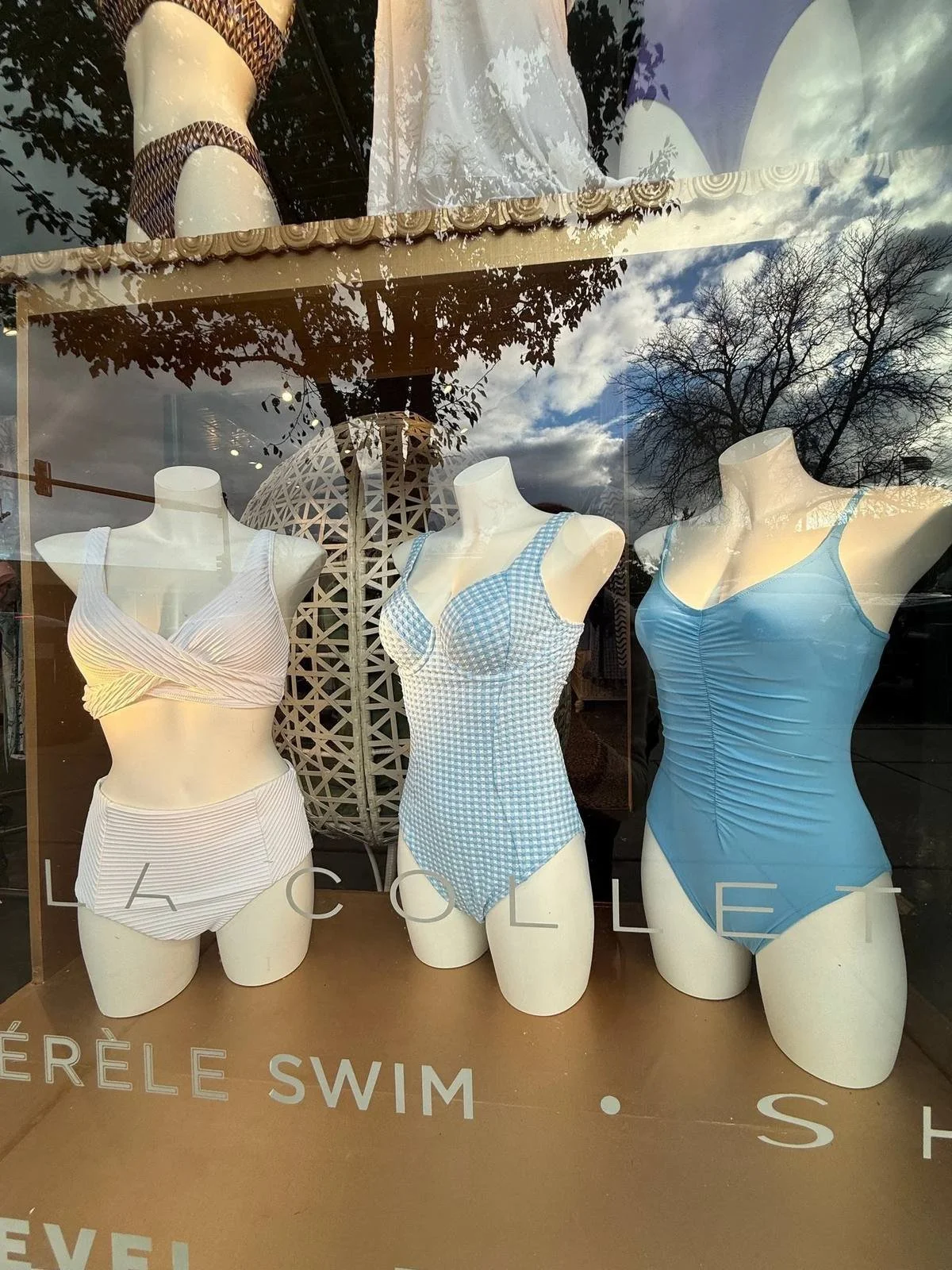 Three swimsuits in white, blue gingham and pale blue on mannequins in the Chantilly Lace shop window