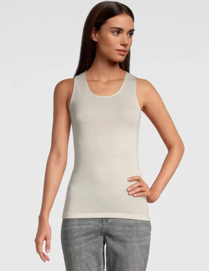 Model in an ivory scoop-neck tank with gray jeans
