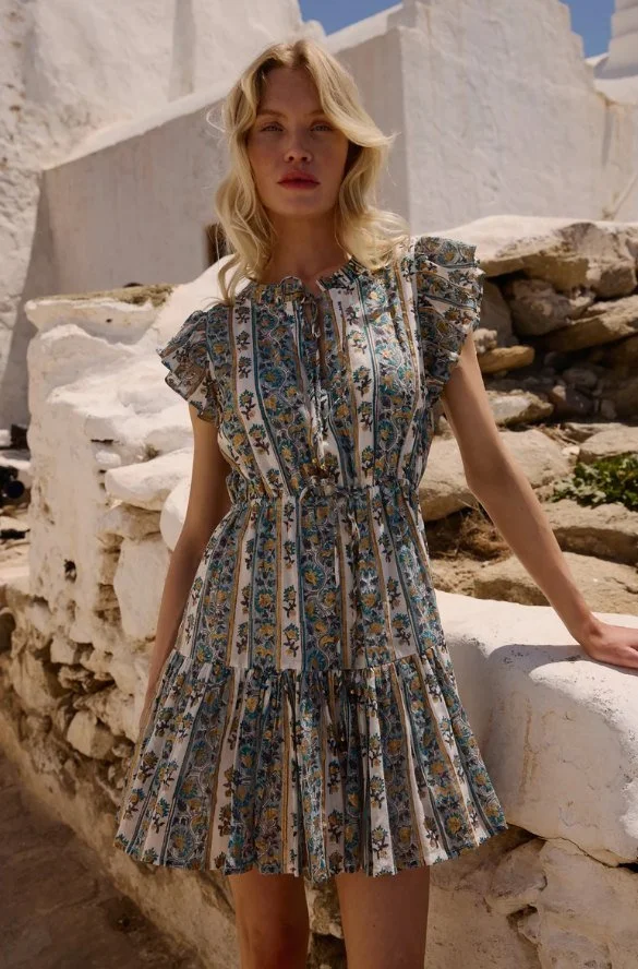Model in a blue floral print tiered mini dress with flutter sleeves