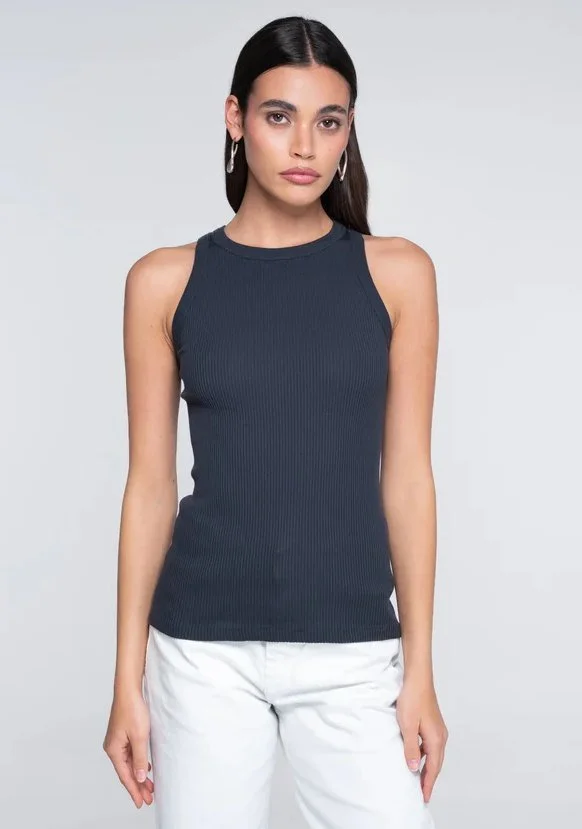 Model in a navy ribbed high-neck tank with white jeans