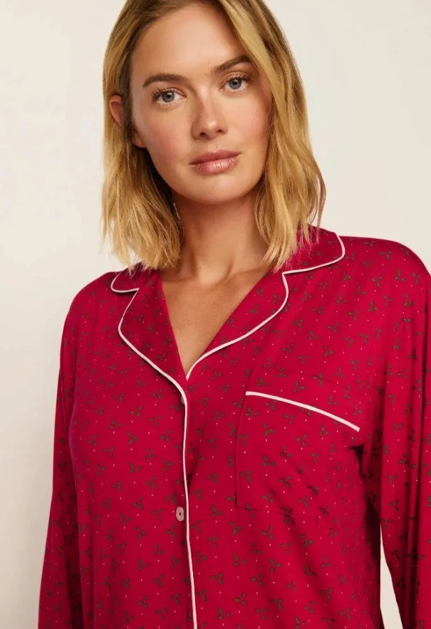 Close-up of a red holly-print long-sleeve pajama top with pale pink piping