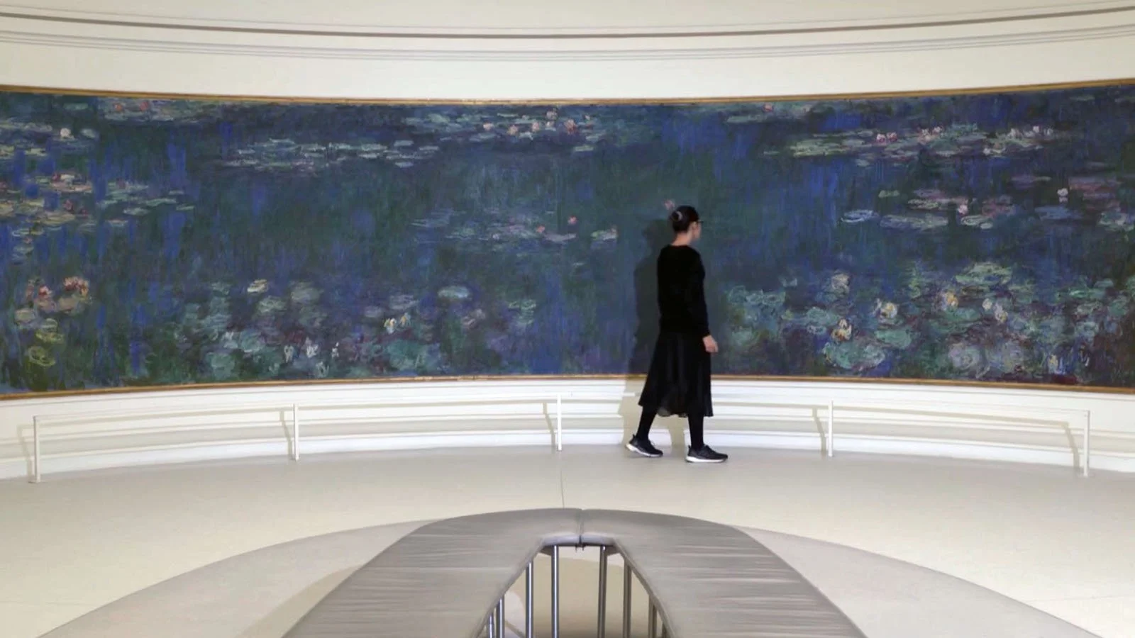 Eine Frau steht vor einem großen impressionistischen Gemälde im Museum.