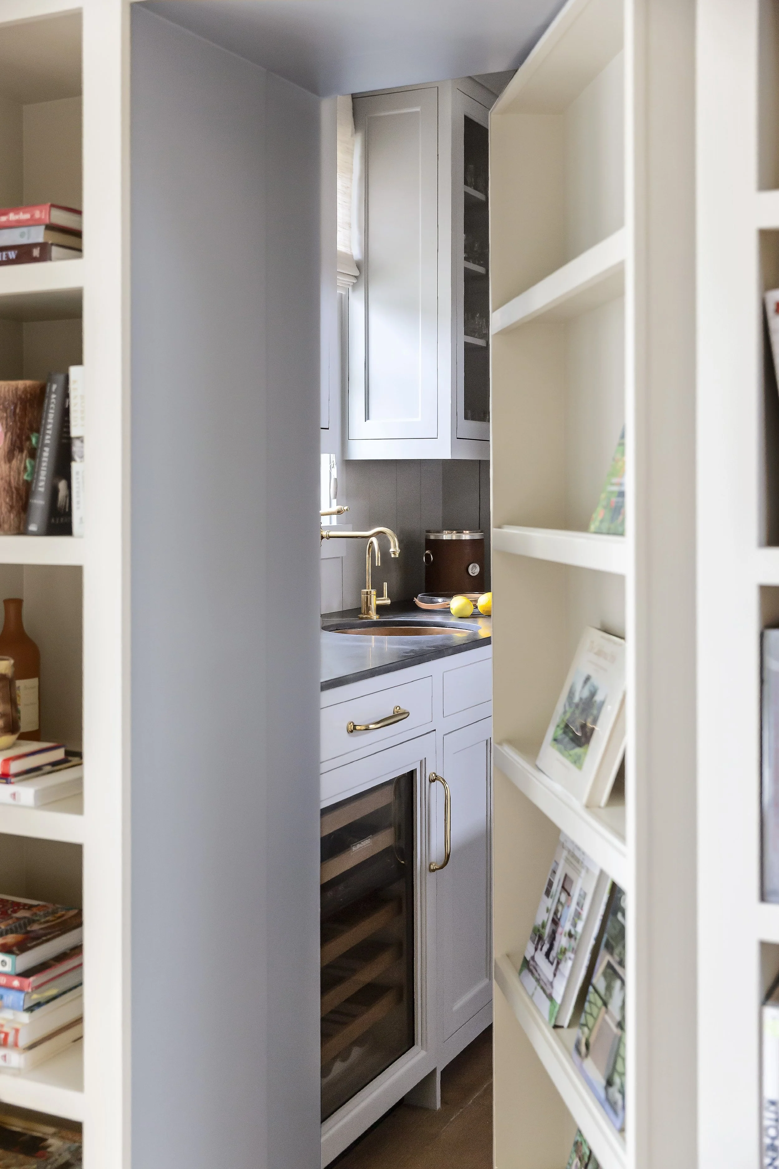 Pantry nook with built-in shelving, brass faucet and gray cabinetry