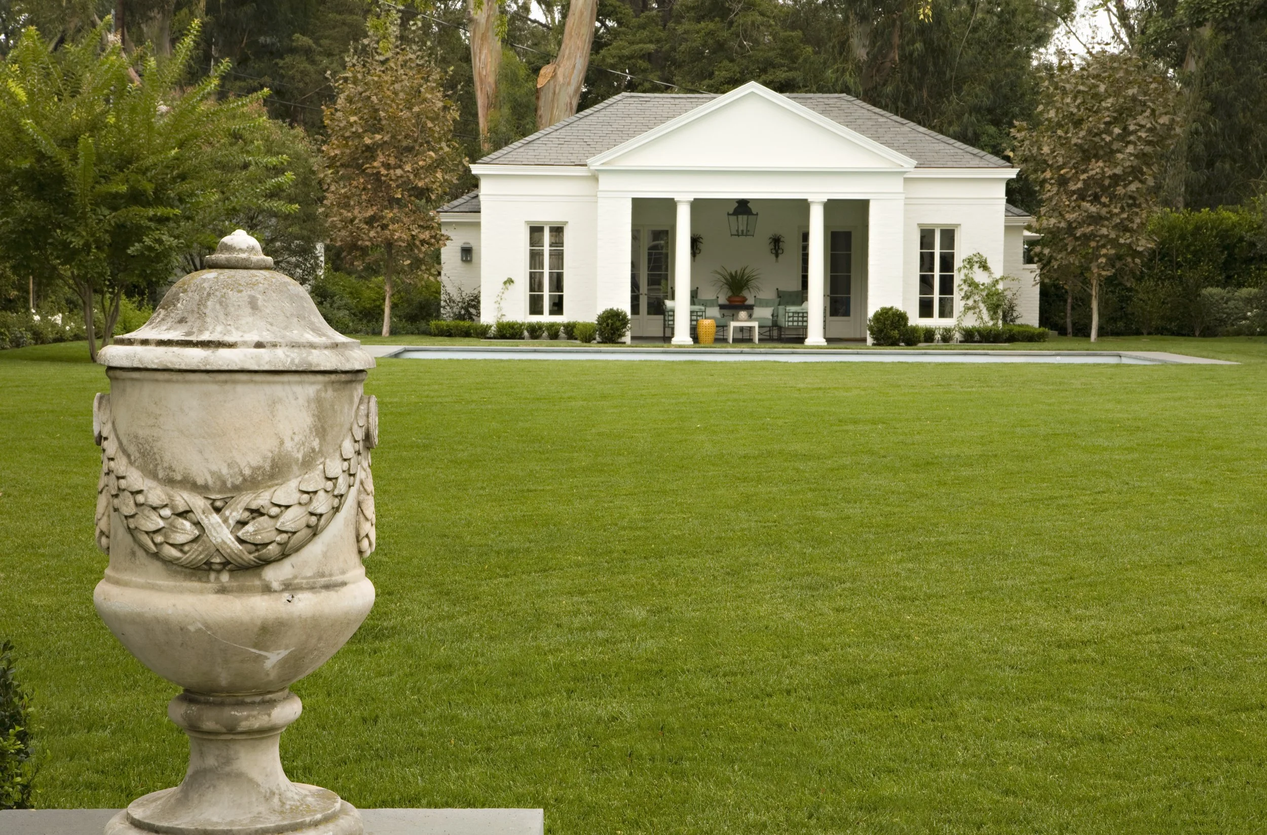 Stone urn on the lawn with a white pavilion in the distance