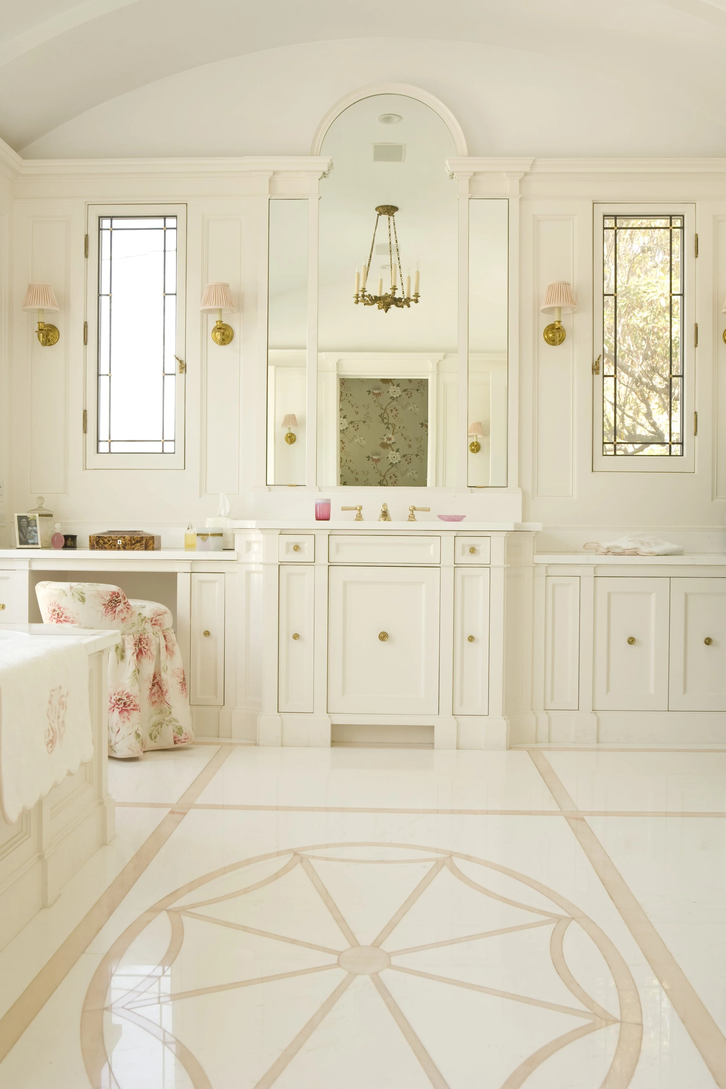 Dressing area with white cabinetry, brass knobs and a floral upholstered stool