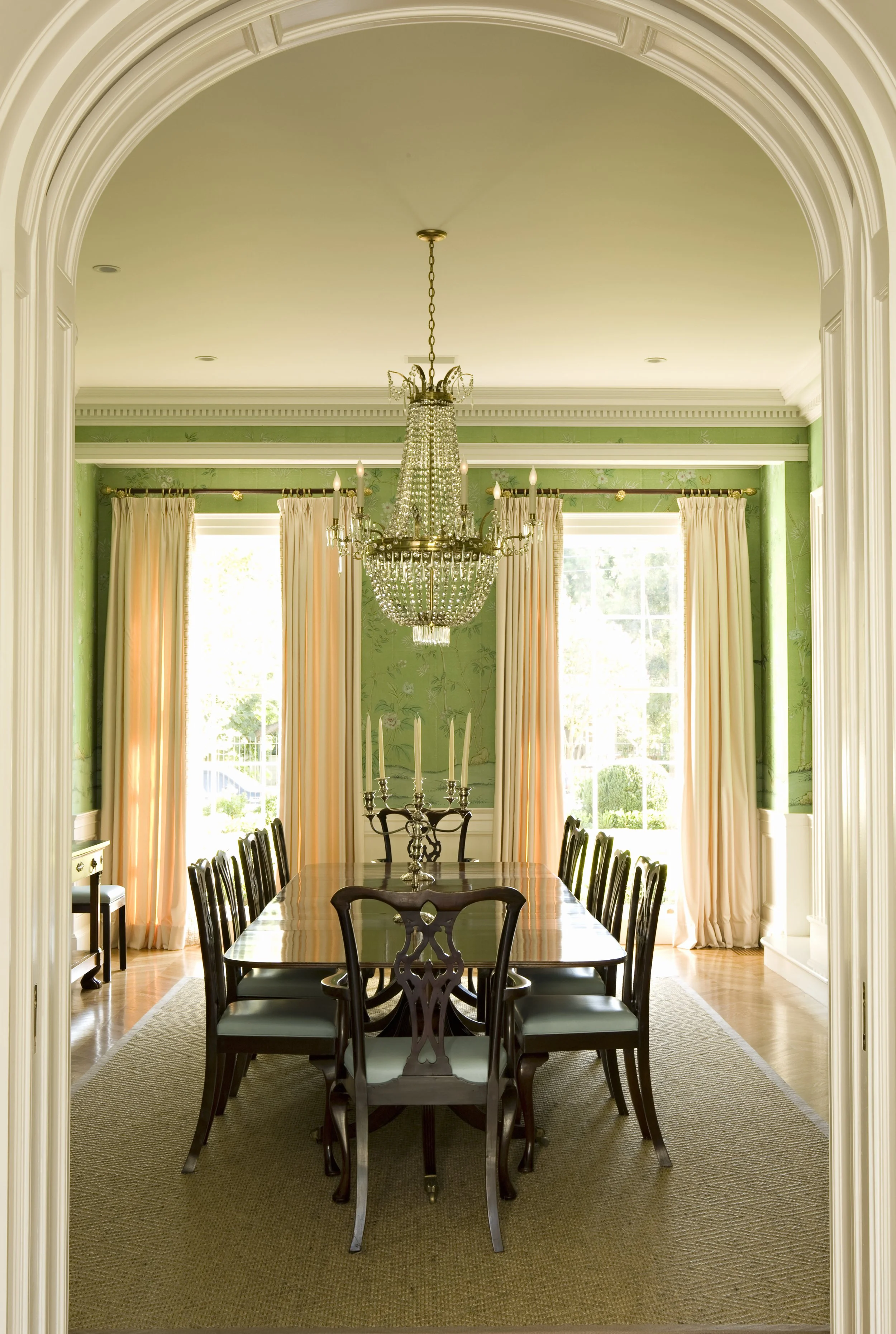Formal dining room with a crystal chandelier, pink silk drapes and green walls