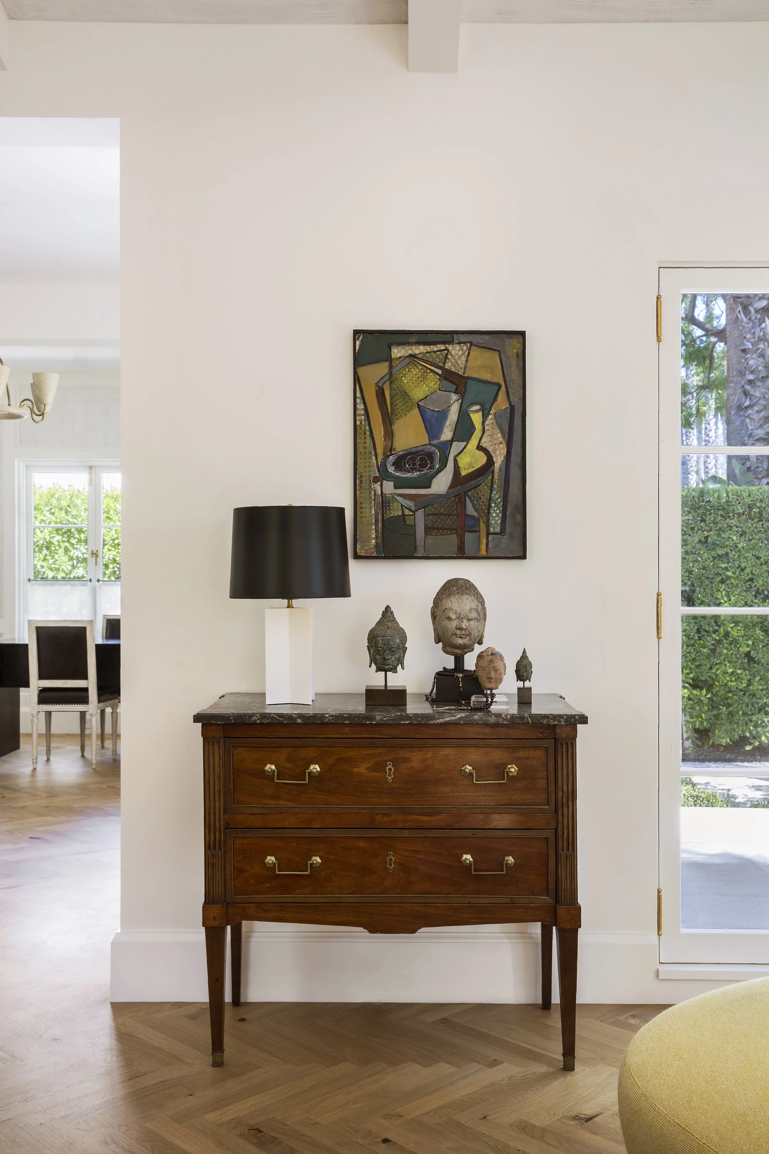 Walnut chest with a cubist painting, black lamp and a carved head