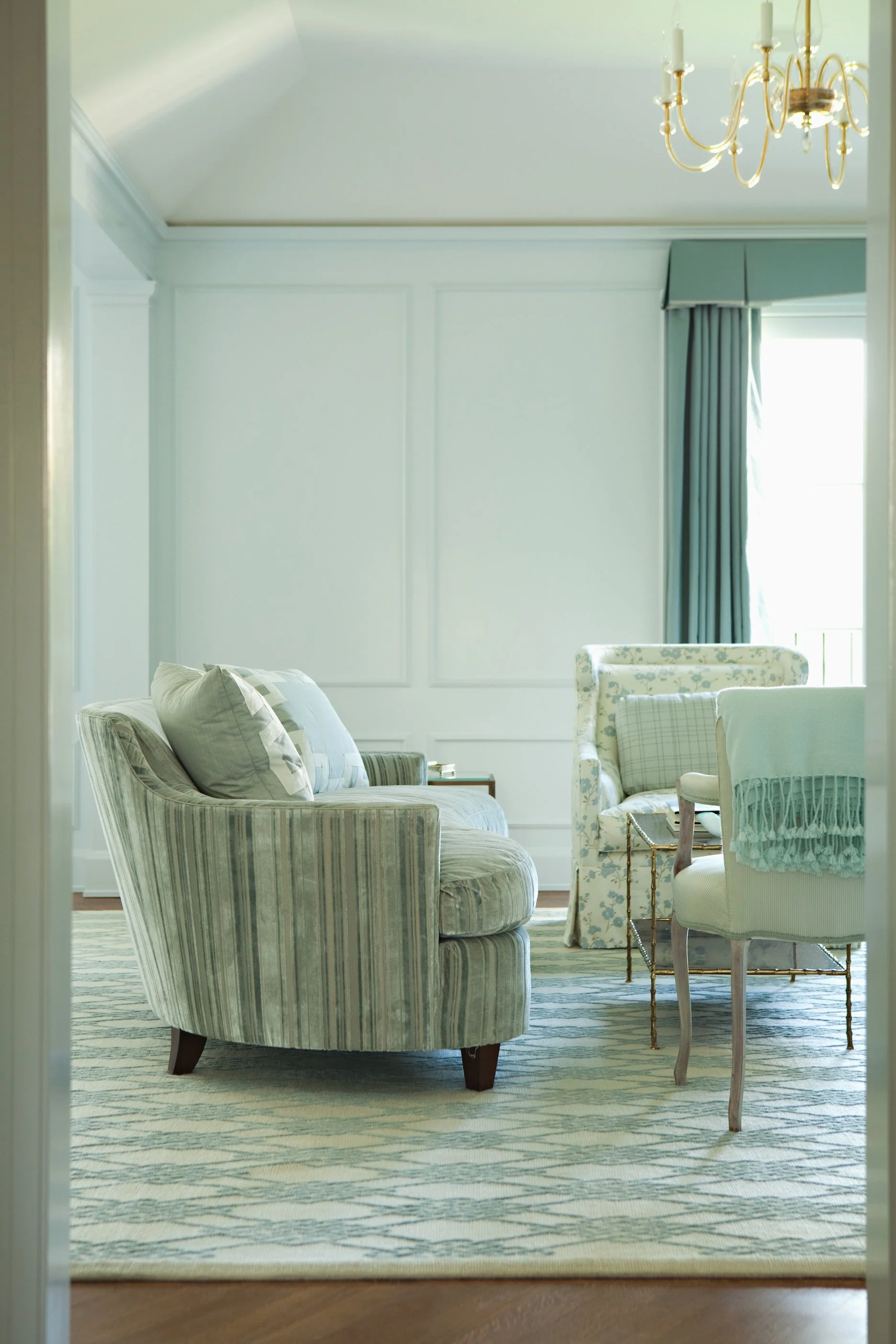 Sitting area with striped and floral chairs, celadon walls and teal drapes