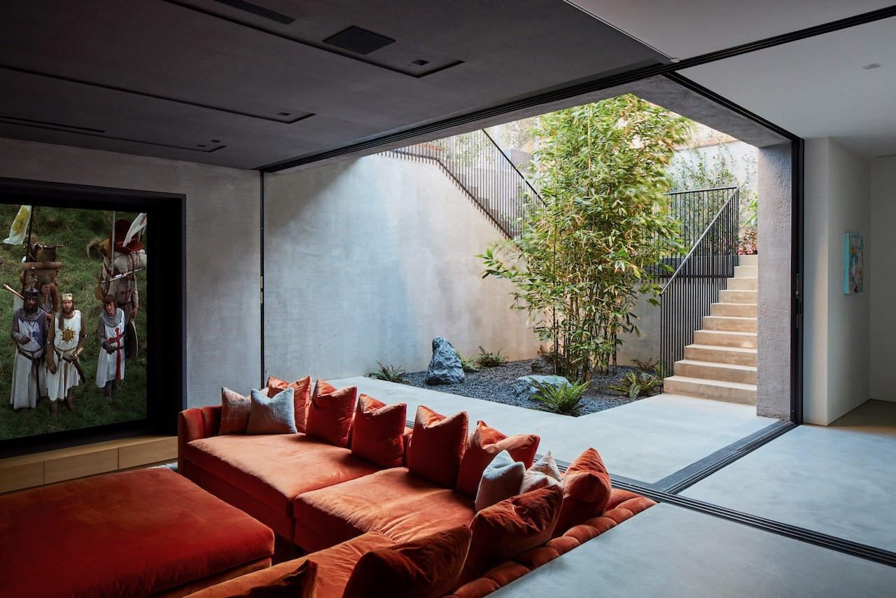 Sunken living area with a rust velvet sectional opening to a garden court