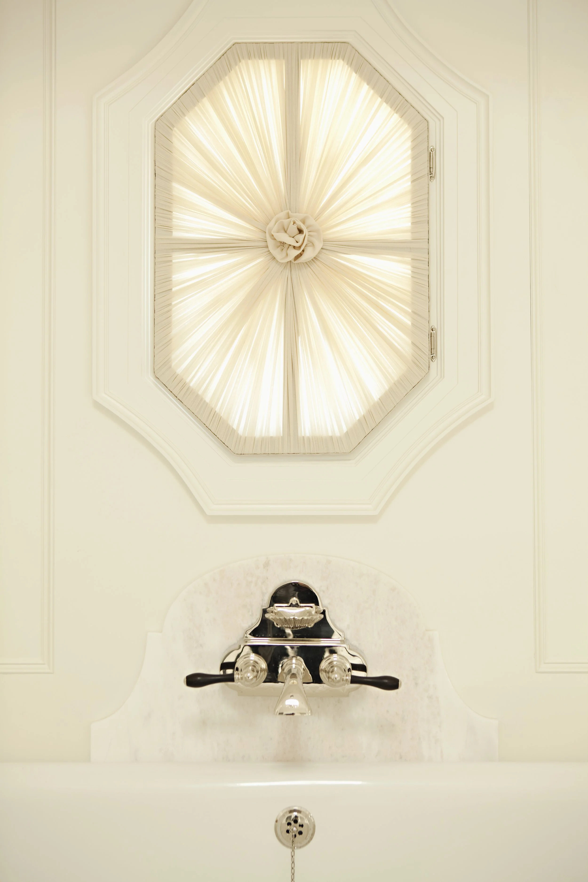 Octagonal window with a gathered sheer shade in a paneled wall