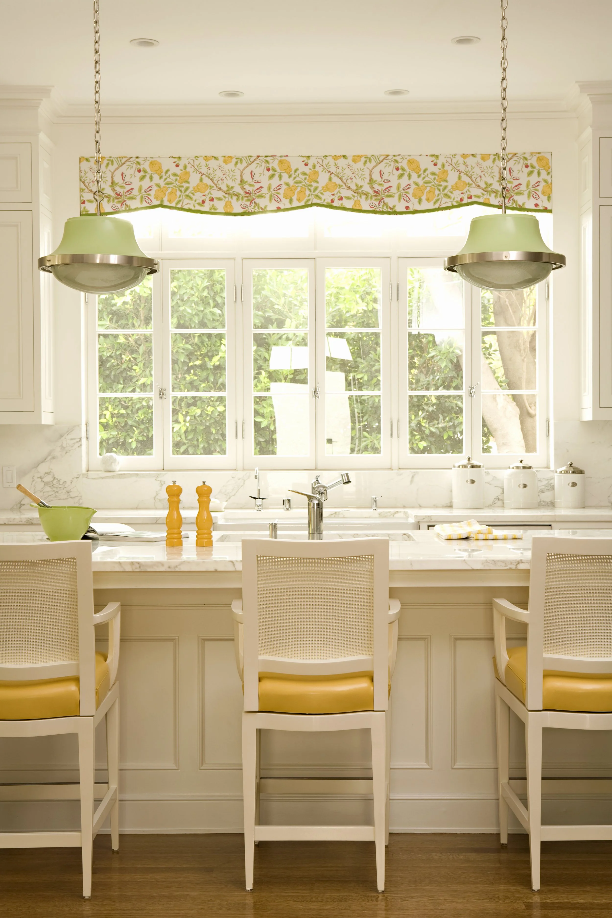 Kitchen island with yellow salt and pepper mills beneath a bank of windows