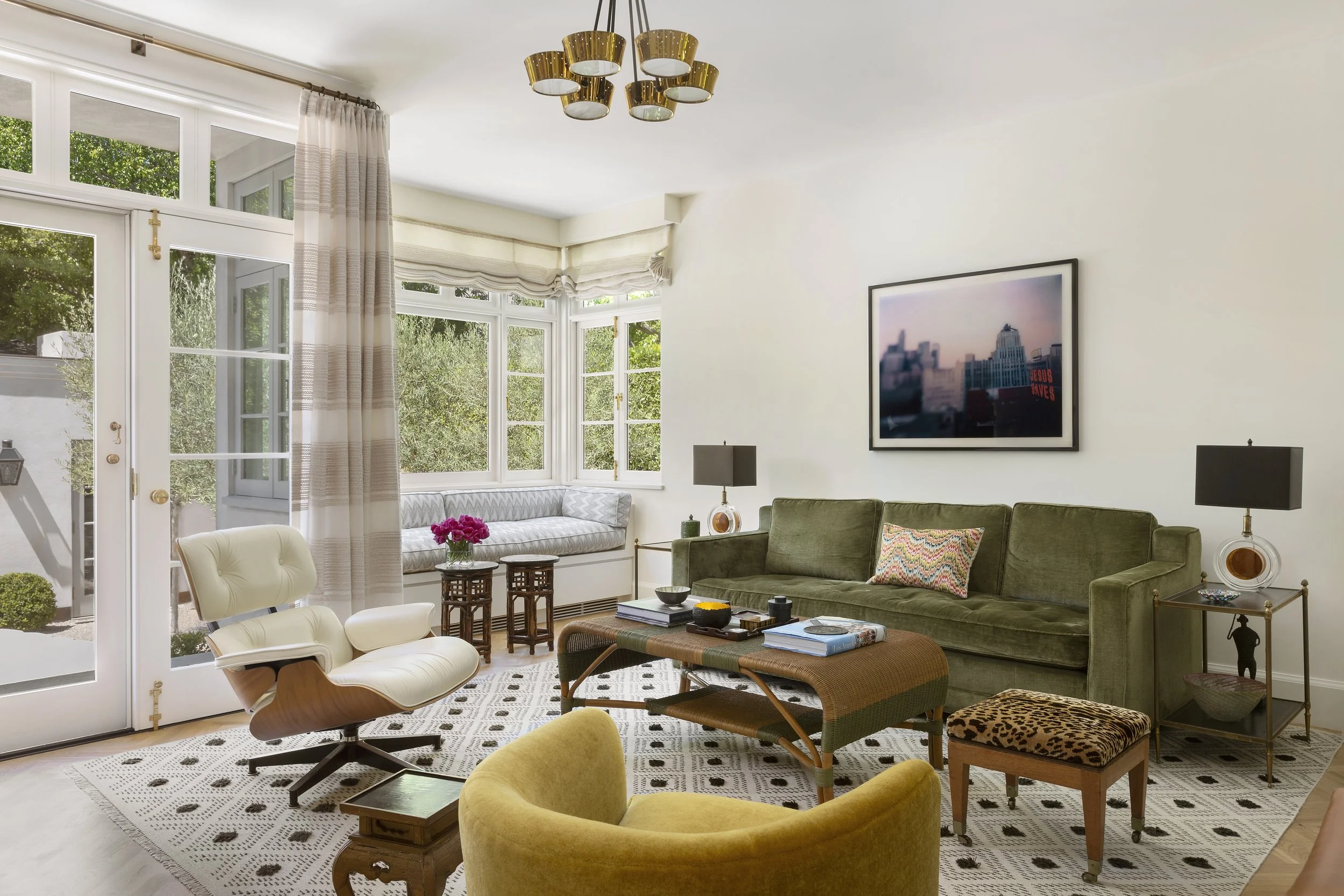 Living room with an olive velvet sofa, mustard chair, cowhide stool and graphic rug