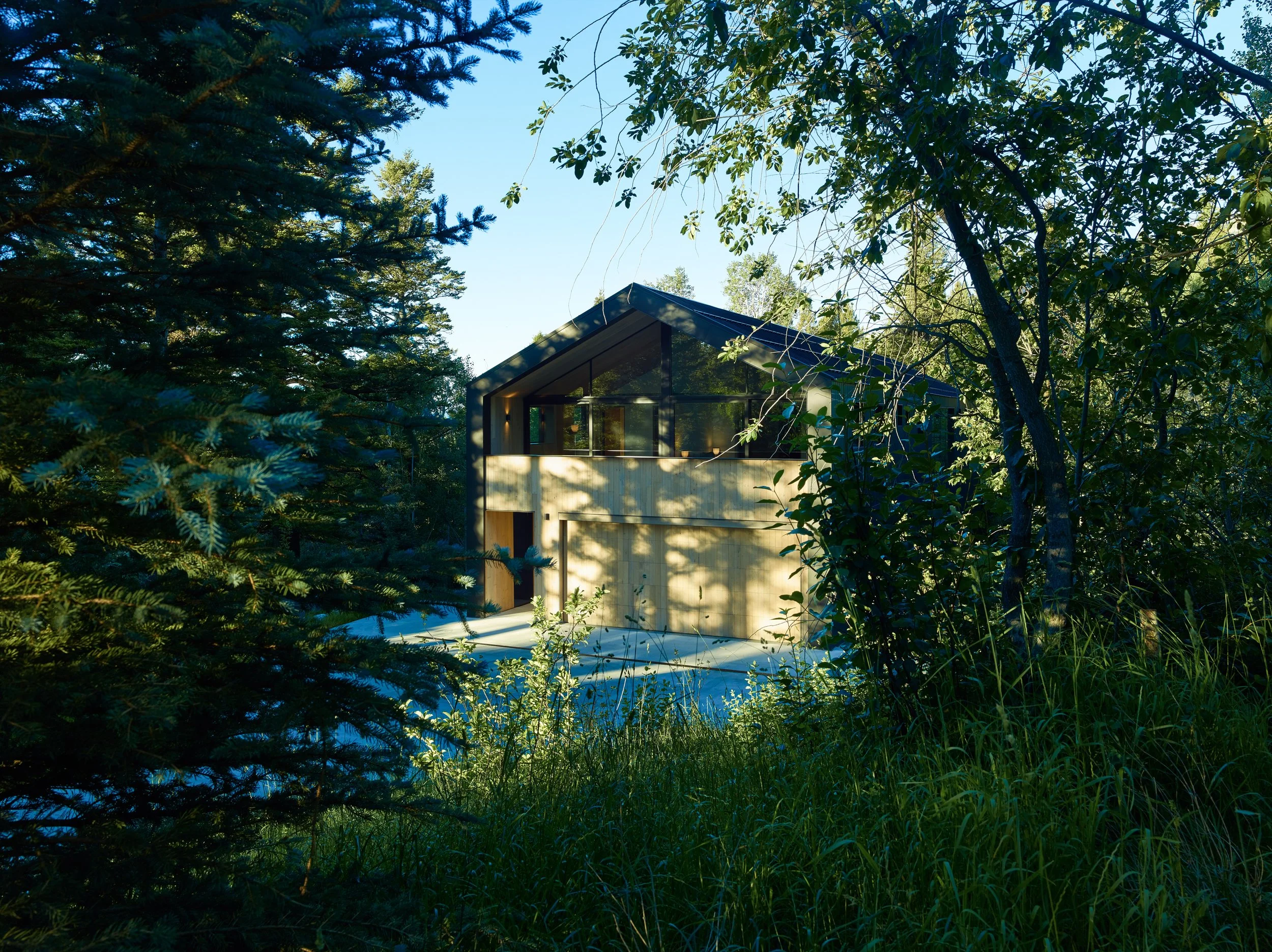 Gabled pavilion among trees with a pool in the foreground at dusk