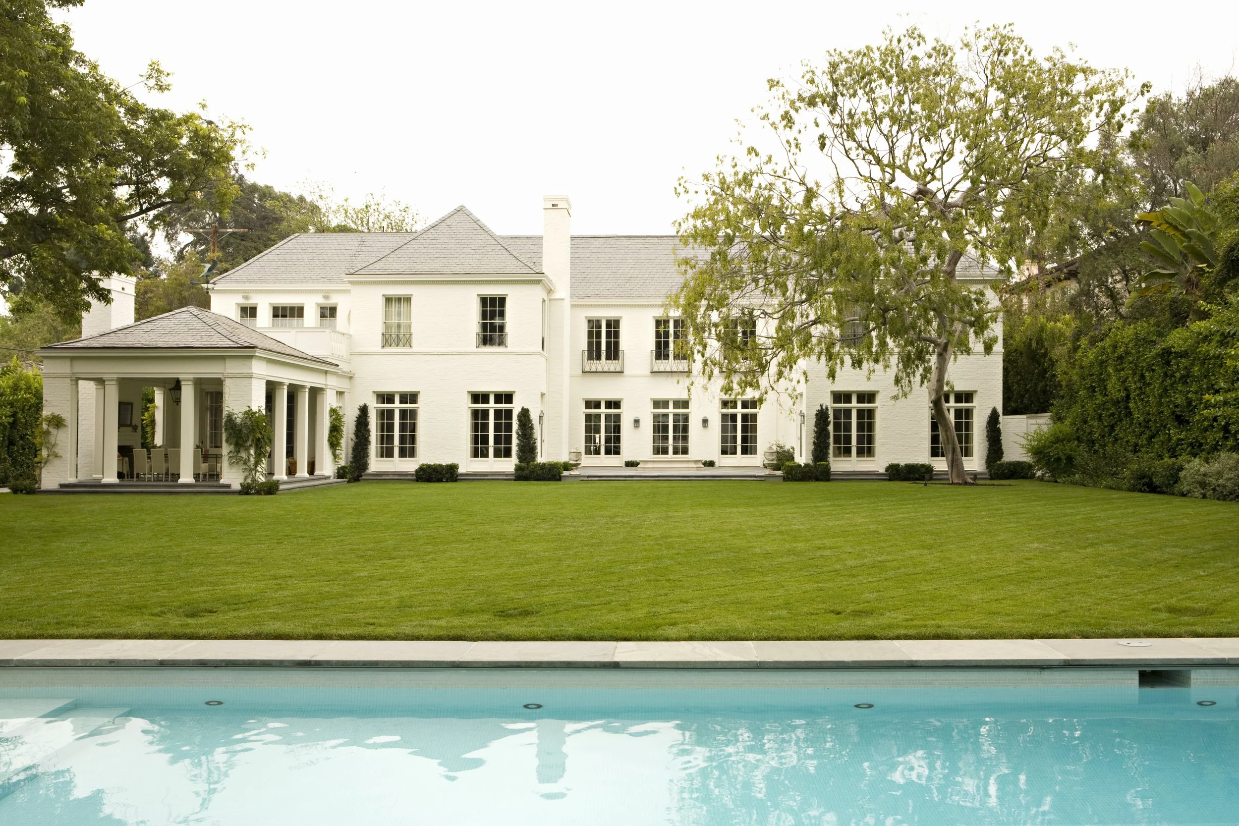 Back of the white Georgian house across the lawn and pool