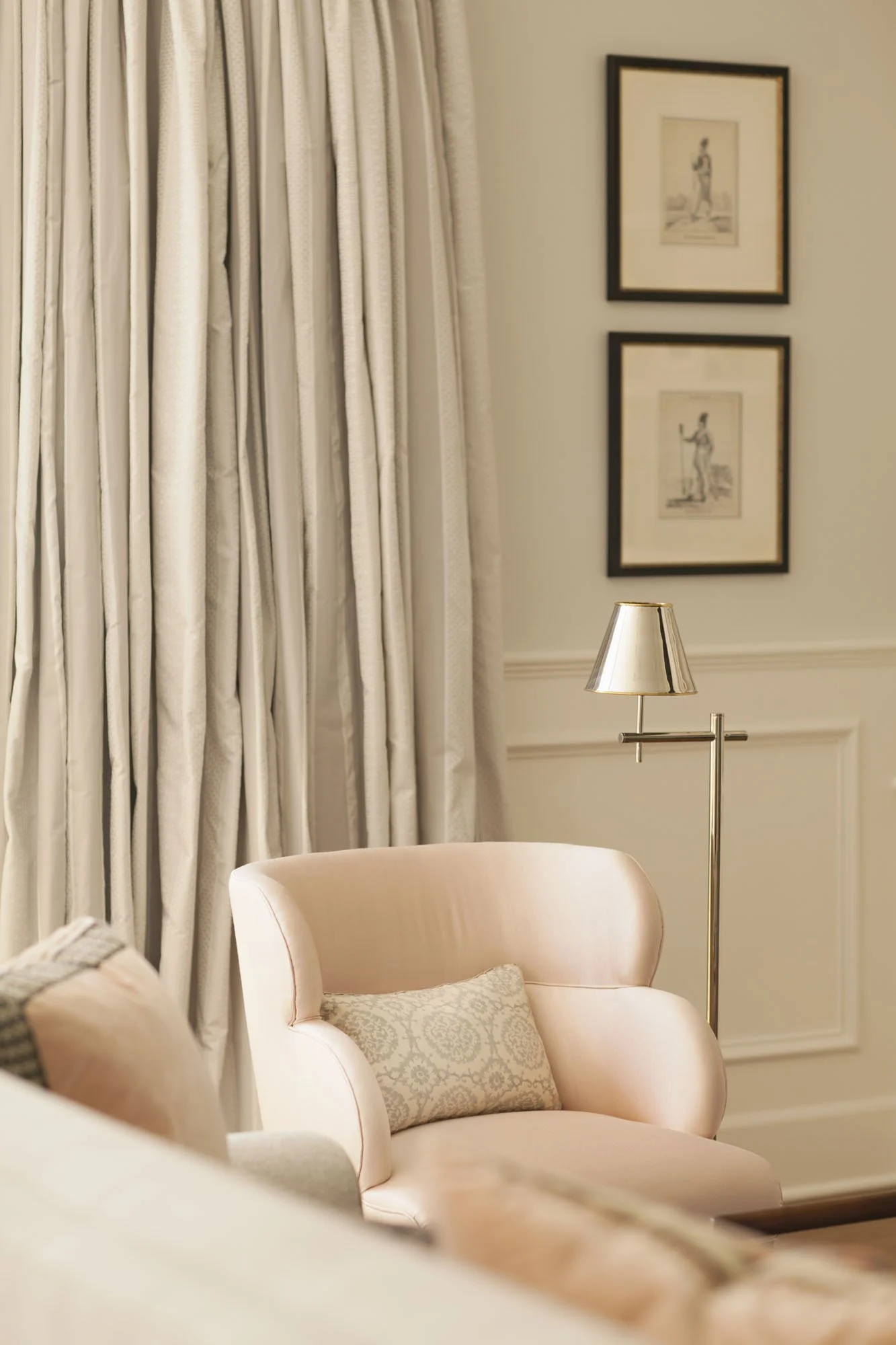 Sitting corner with a blush armchair, brass floor lamp and floor length silk curtains