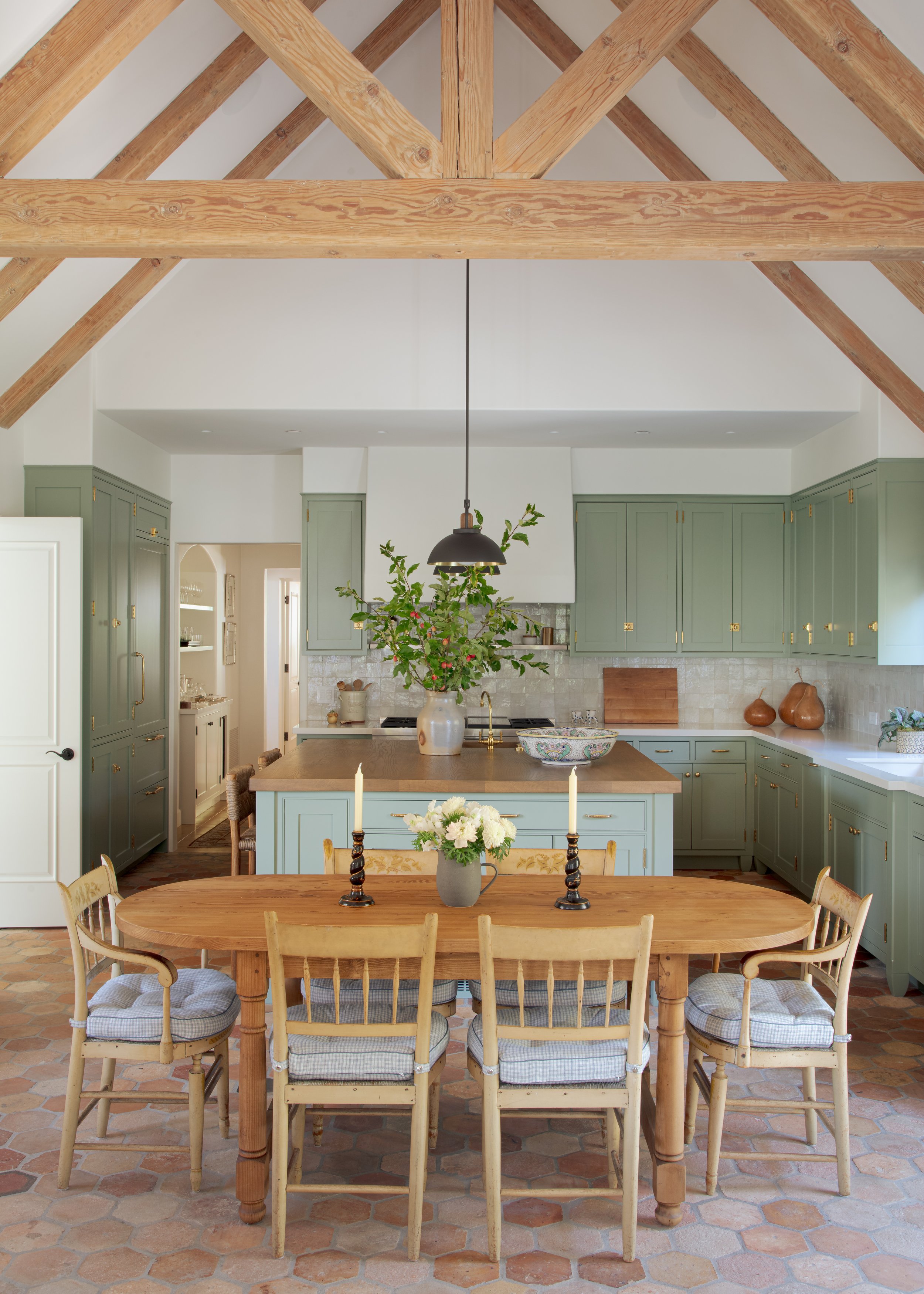 Kitchen with green painted cabinetry, a wood-topped island, a black pendant light and a table set with candles