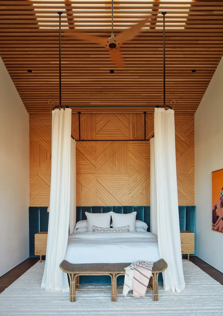 Bedroom with a wood slat ceiling, geometric wood headboard wall, teal velvet headboard and white canopy curtains