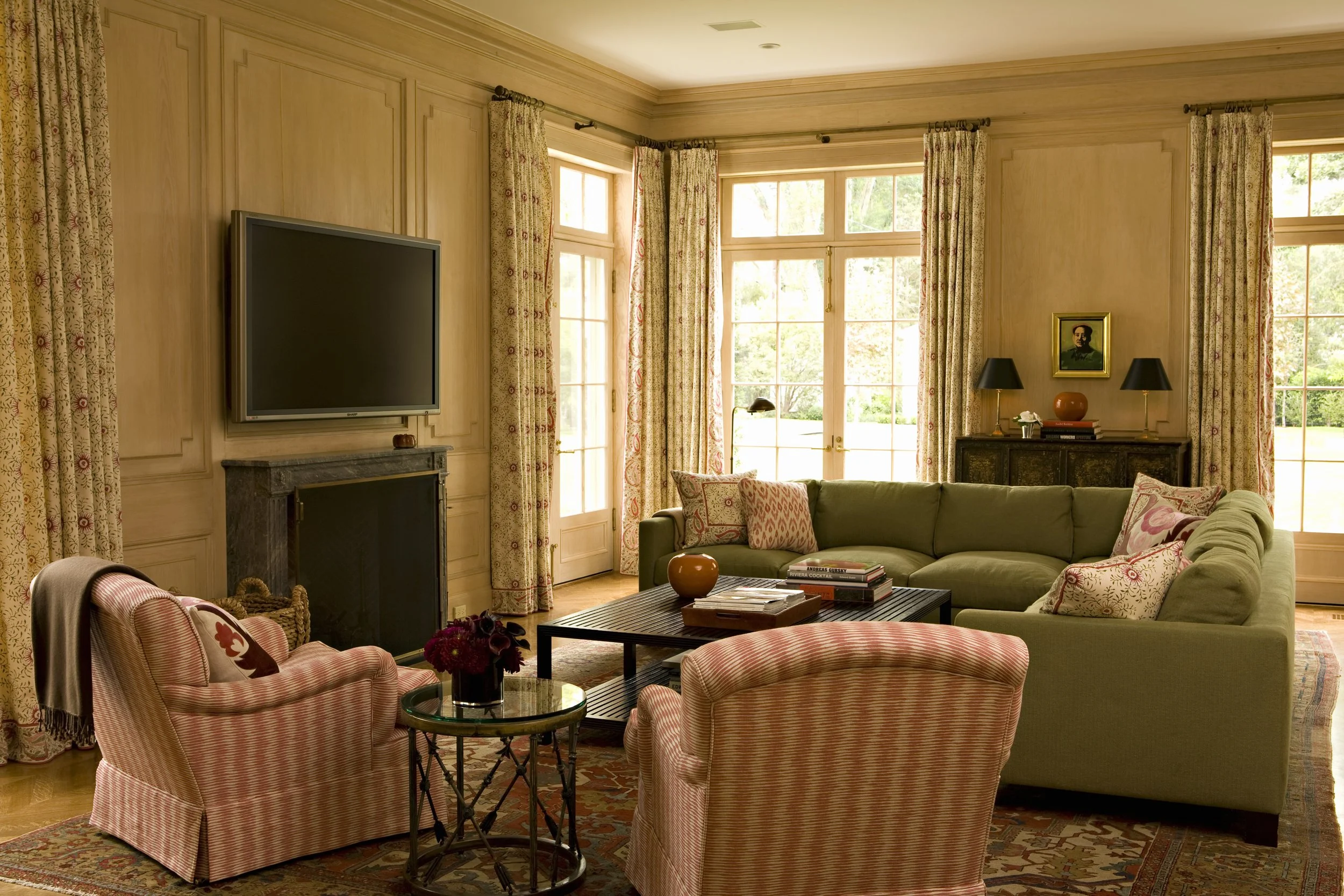 Family room with a green sectional, pink striped chairs and a fireplace