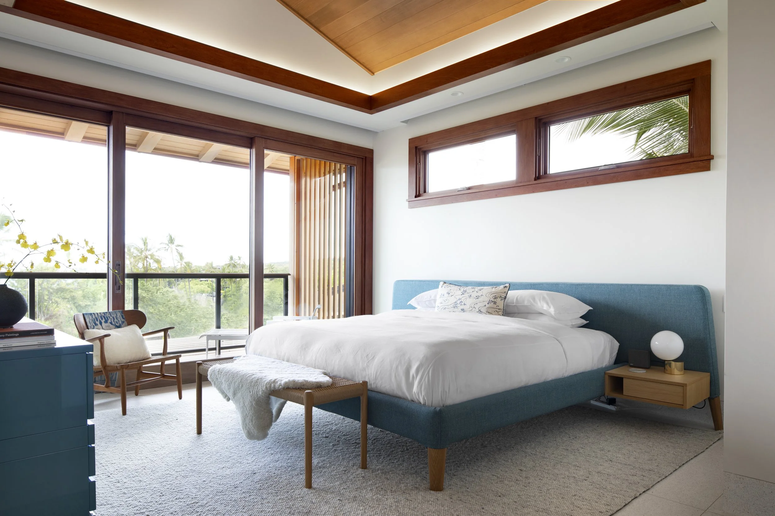 Bedroom with a teal bed, wood ceiling trim and balcony doors