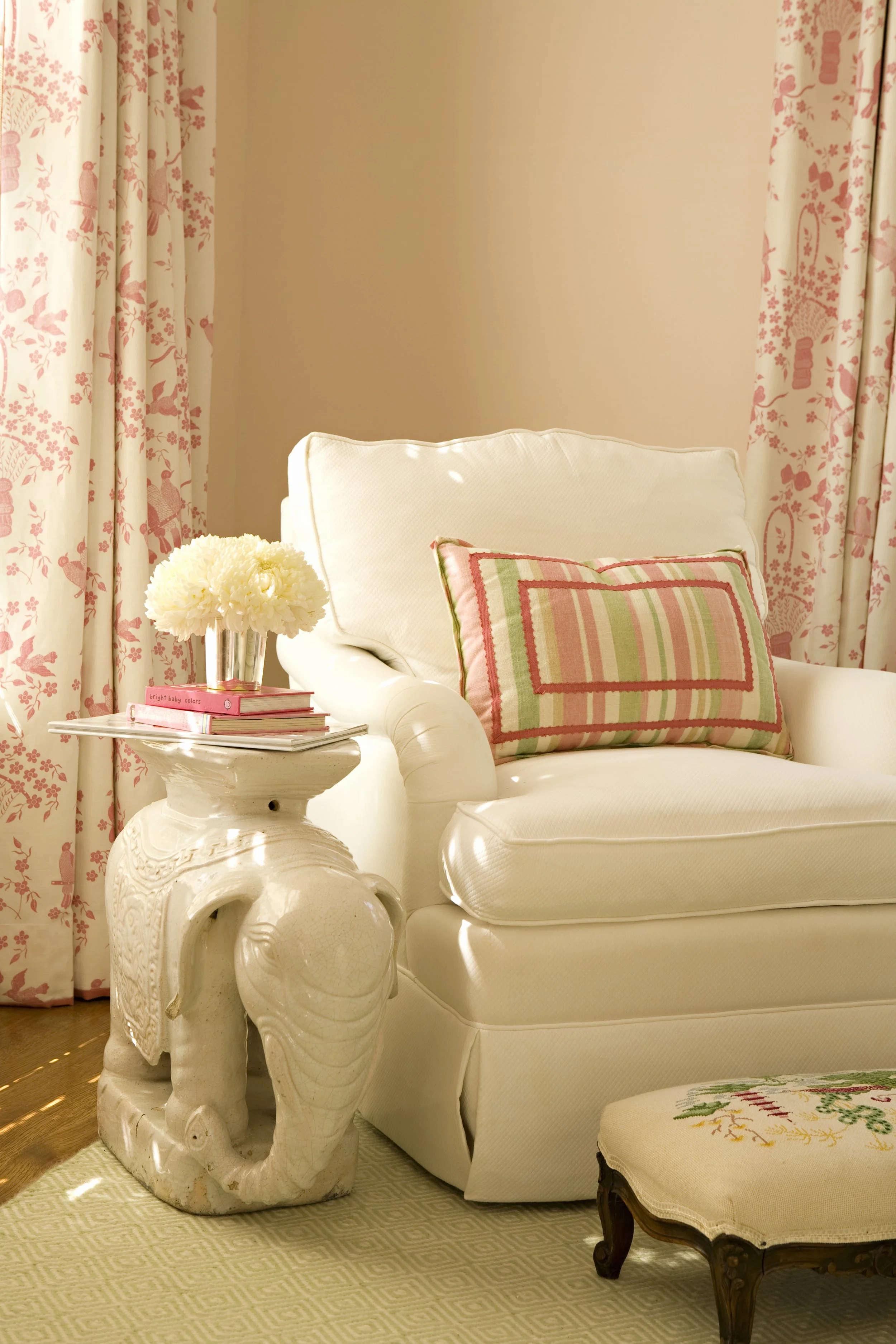 White slipcovered chair, elephant side table and pink floral drapes
