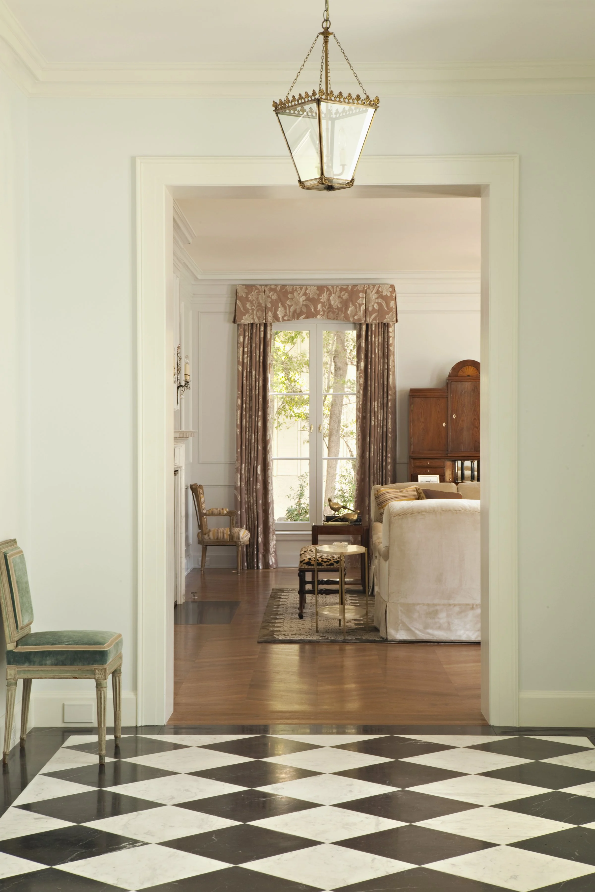 Sitting room with floral drapes at a French door, an antique cabinet and a cream sofa