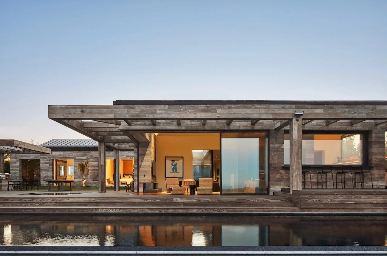 Reclaimed wood pavilion house reflected in a still pond at dusk