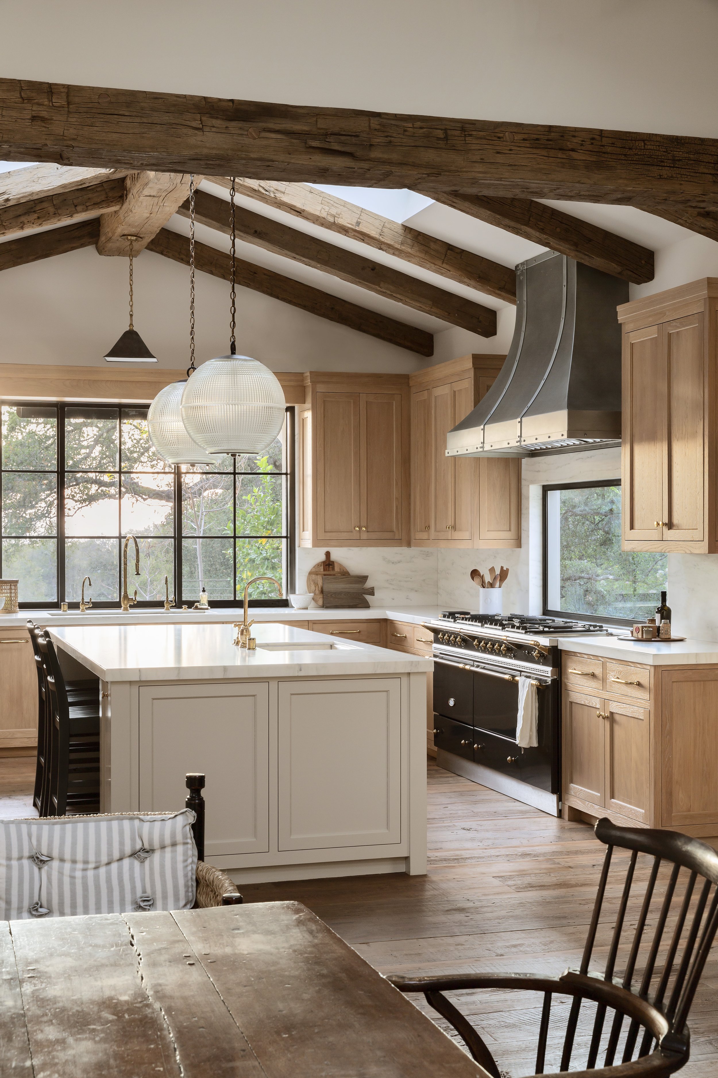 Kitchen with natural wood cabinets, an island, glass pendants and a black range