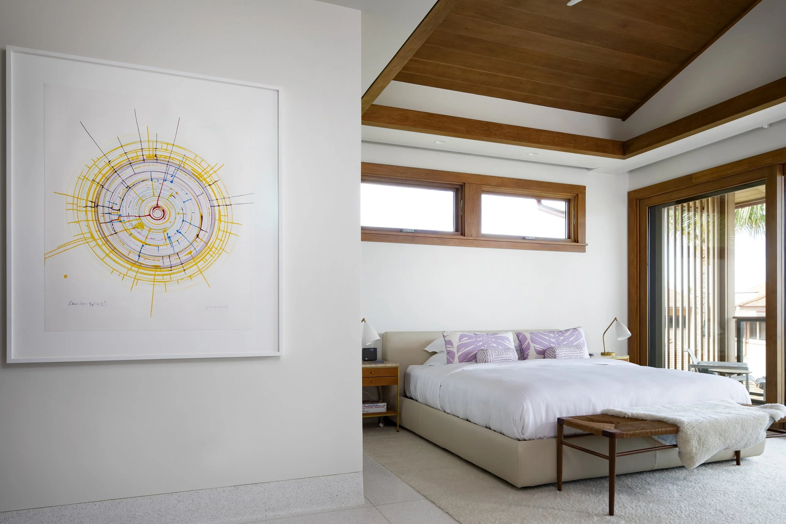 Guest bedroom with a colorful abstract print, lavender pillows and a wood ceiling
