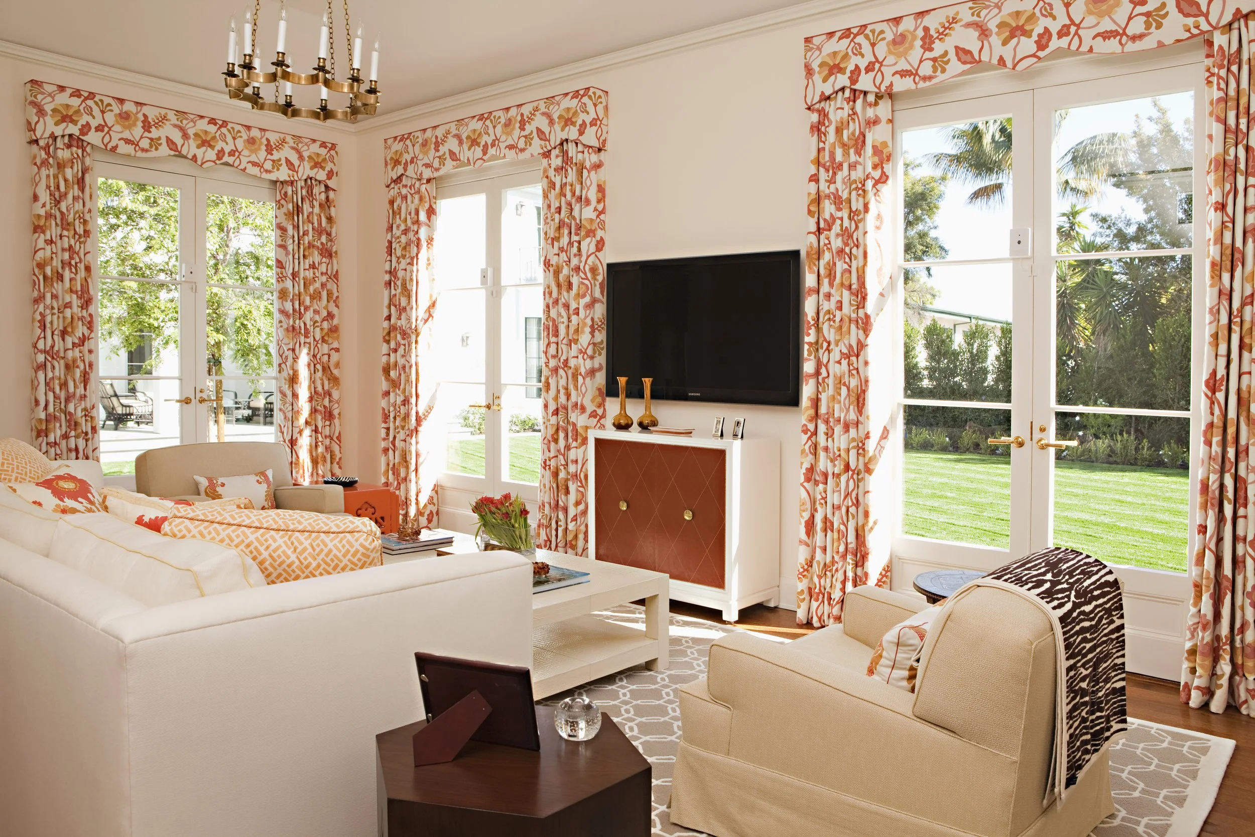 Family room with coral floral drapes, white sectional and French doors to the lawn
