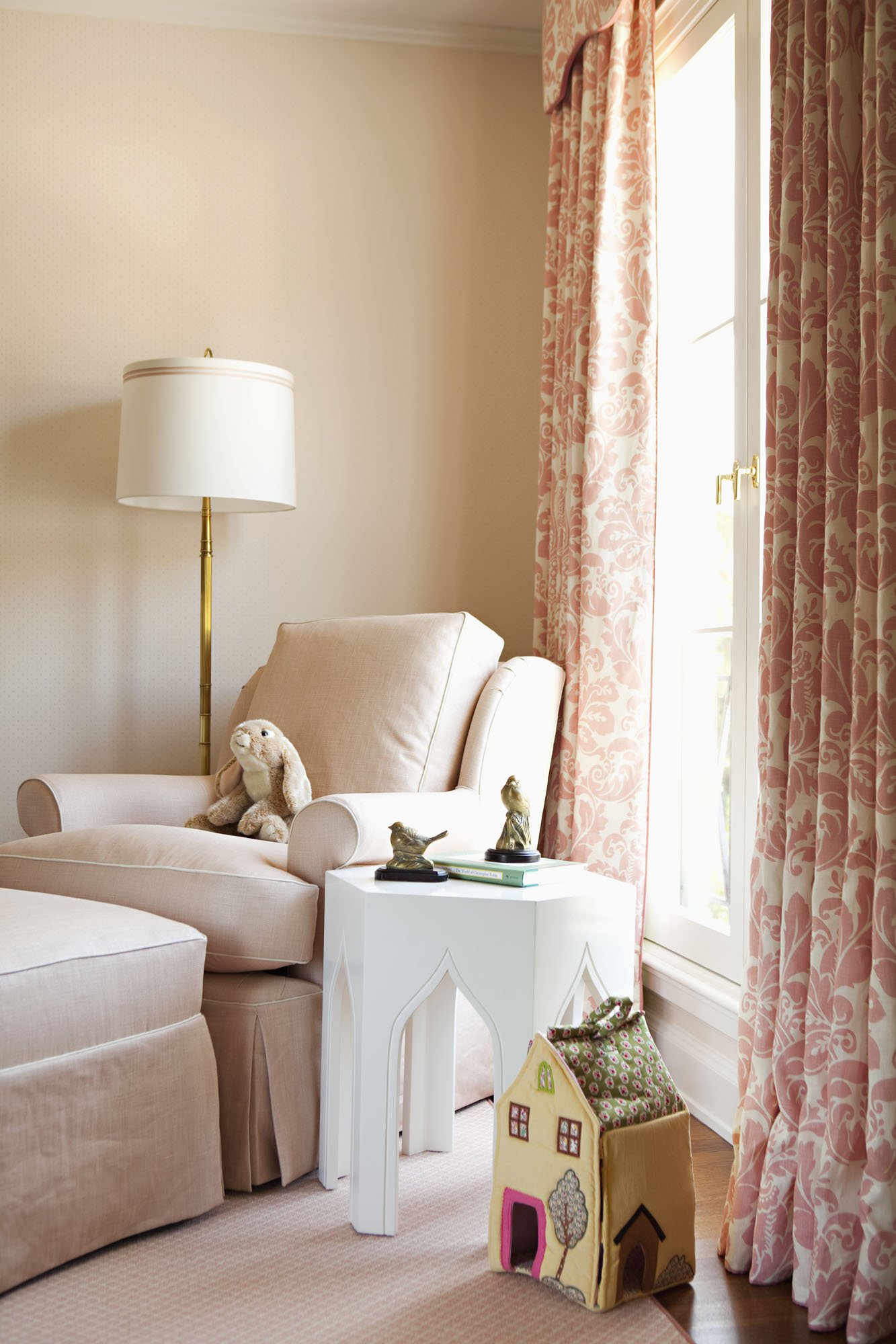 Reading chair with a stuffed rabbit, floor lamp and coral floral curtains