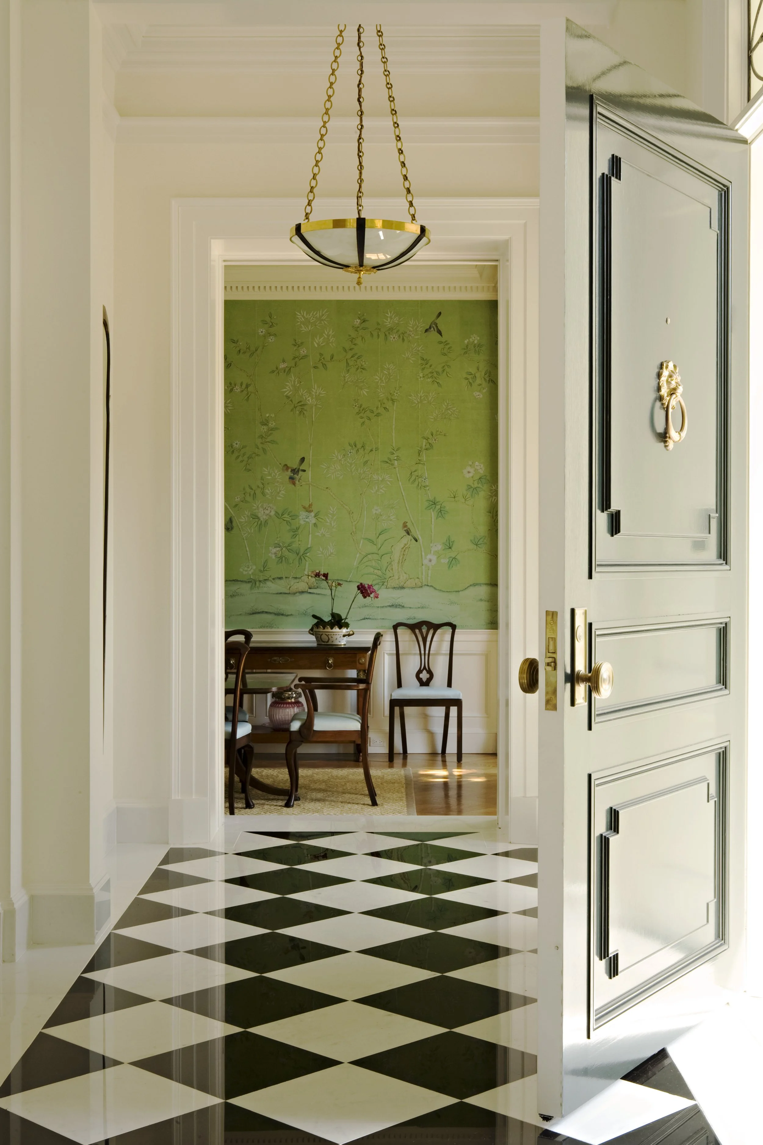 Pocket doors opening to a dining room with green chinoiserie wallpaper