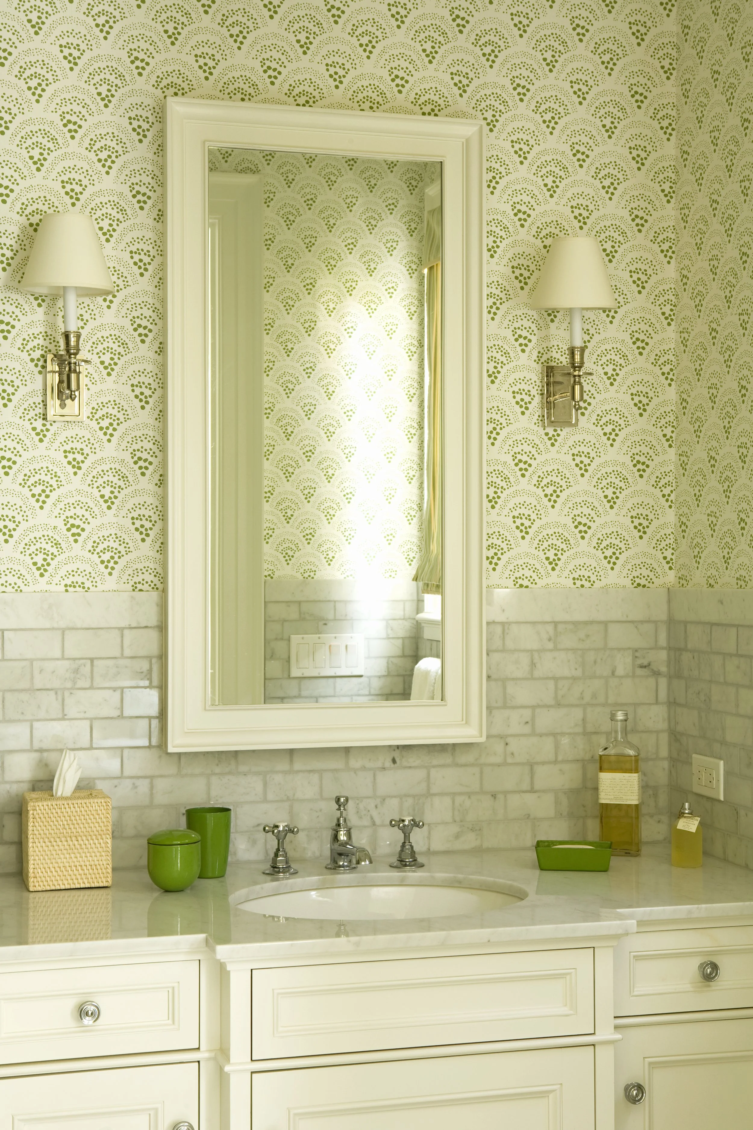 Bath with green fan pattern wallpaper, marble subway tile and a framed mirror