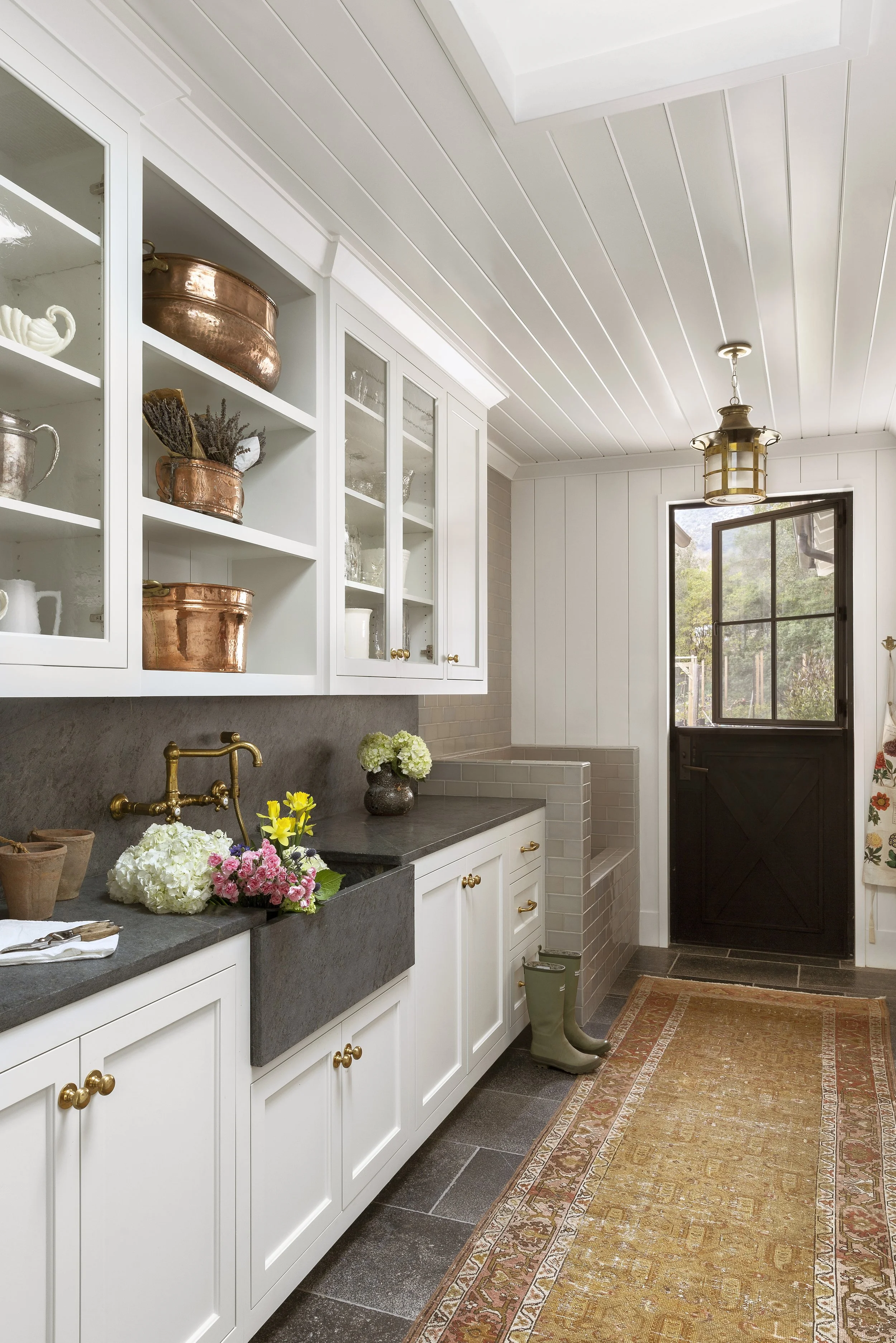 Mudroom with copper pots, a black Dutch door and a lantern