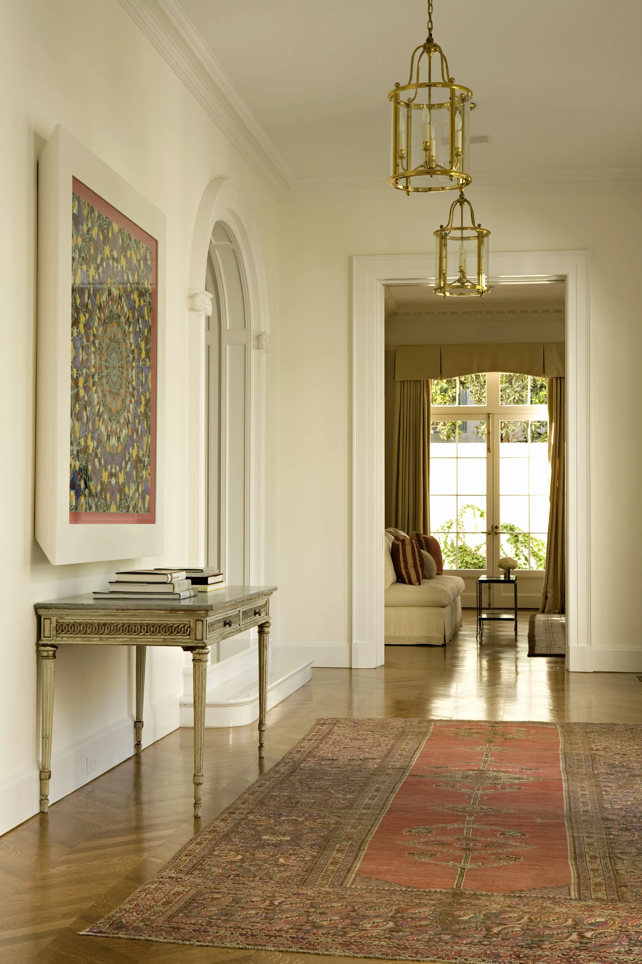 Hallway with a gray console, framed textile art and a view to a sitting room