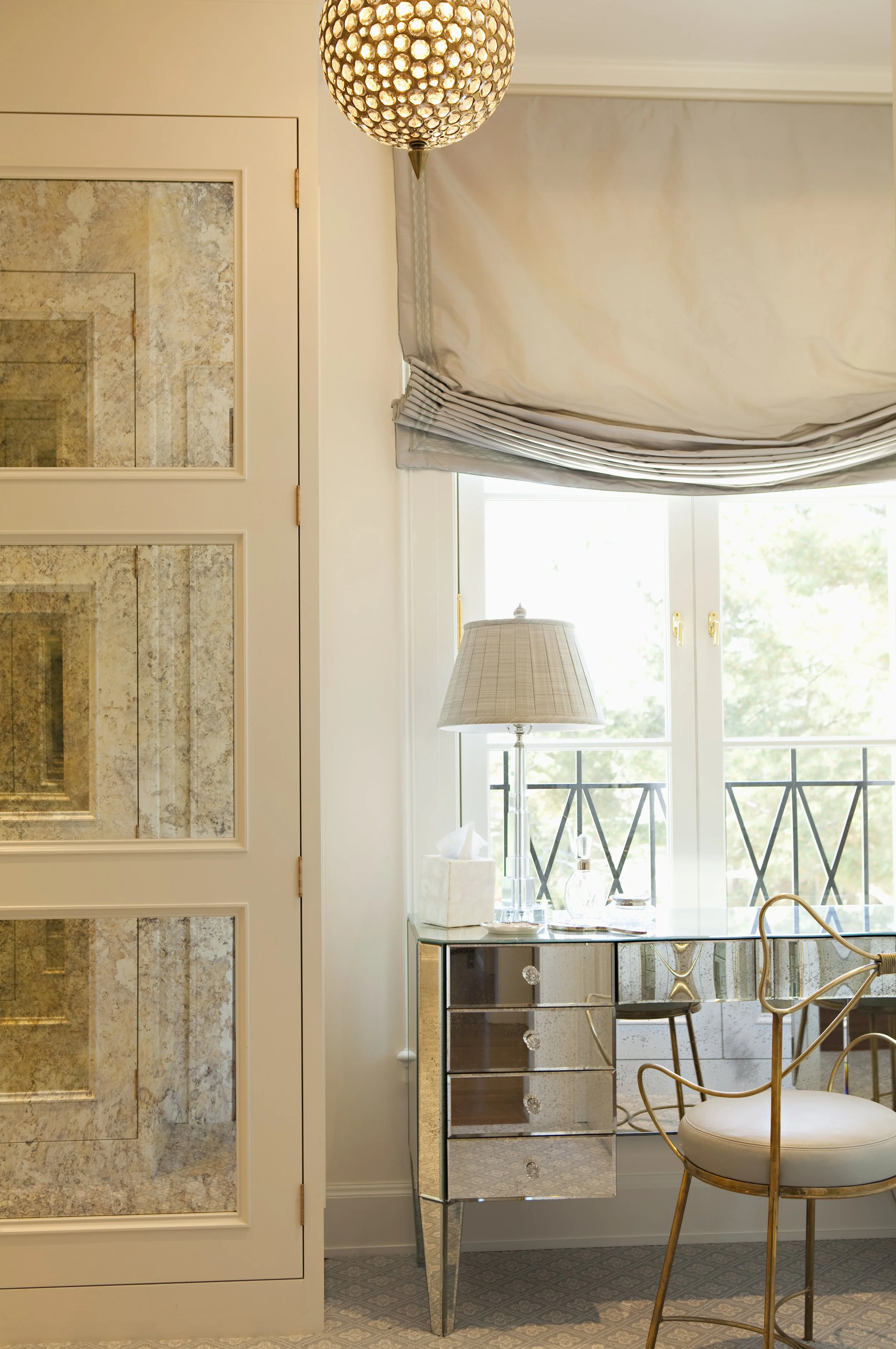 Mirrored door and a balcony view with a lamp and gray roman shade