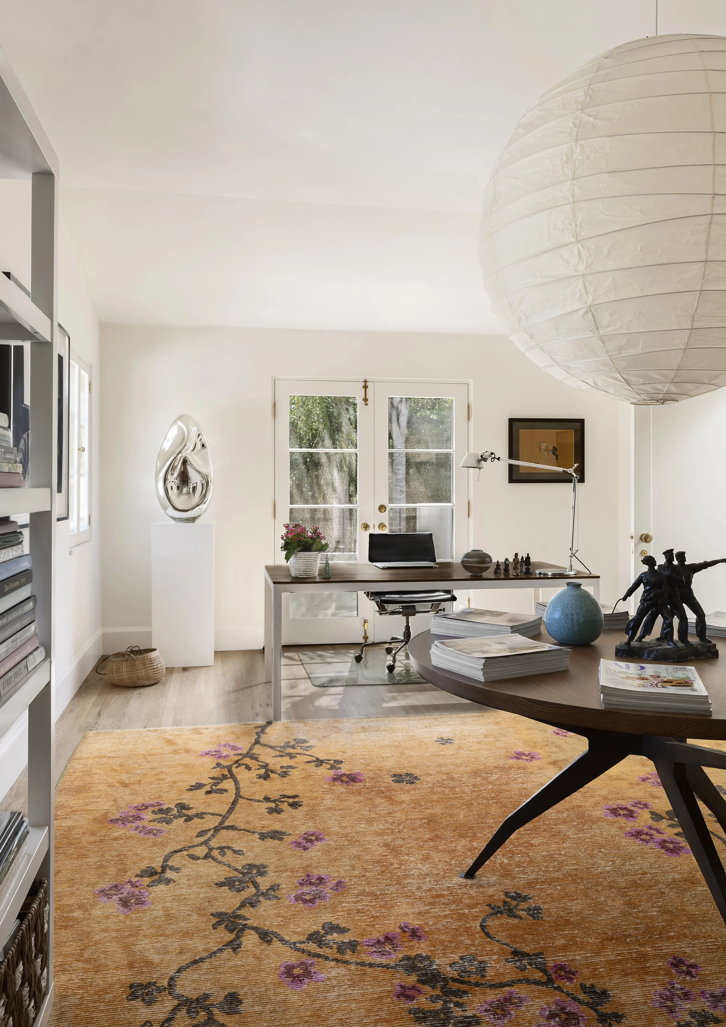 Home office with a round desk, paper lantern pendant and French doors