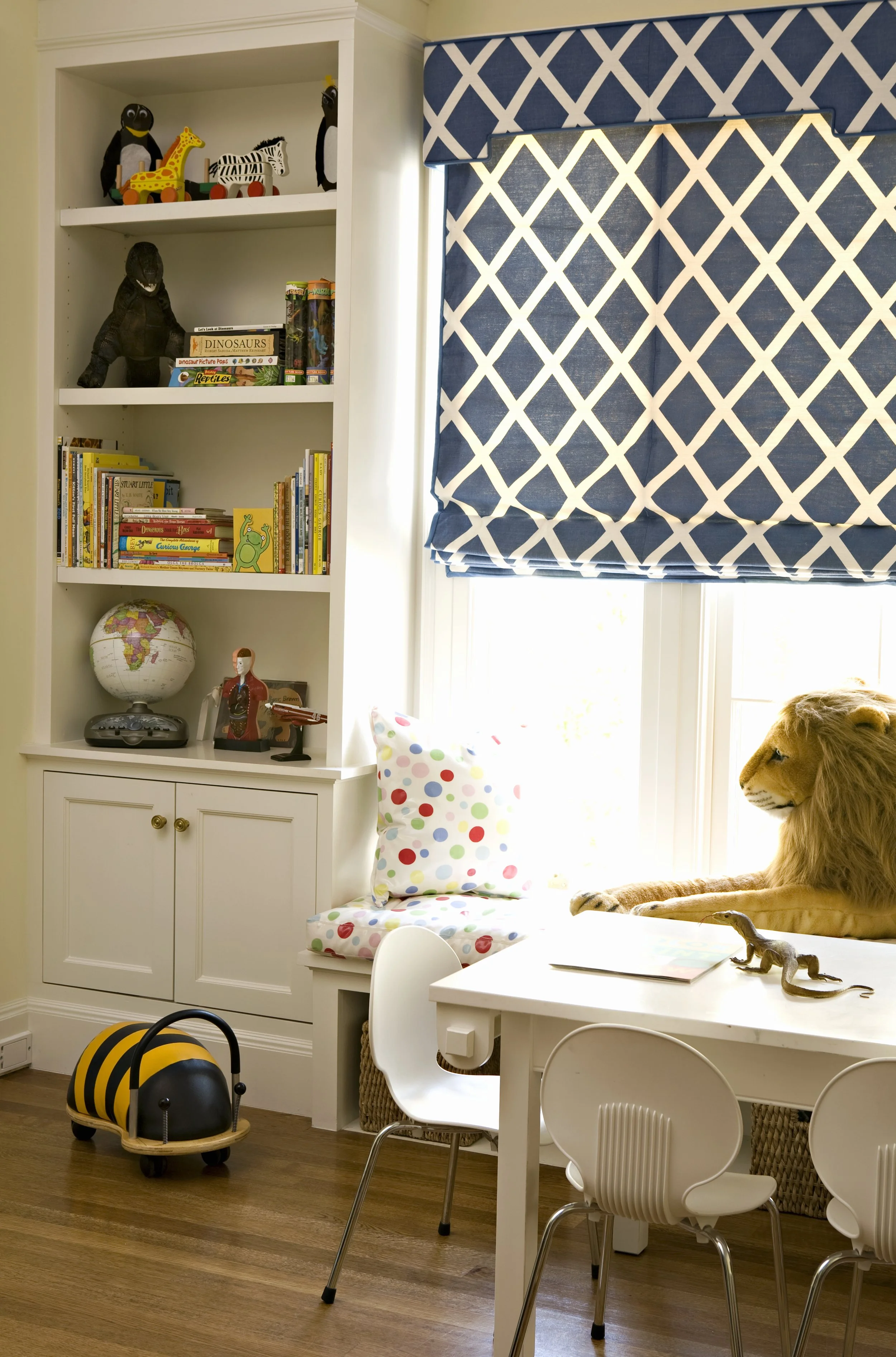 Window seat with built-in shelves, a stuffed lion and a blue lattice roman shade