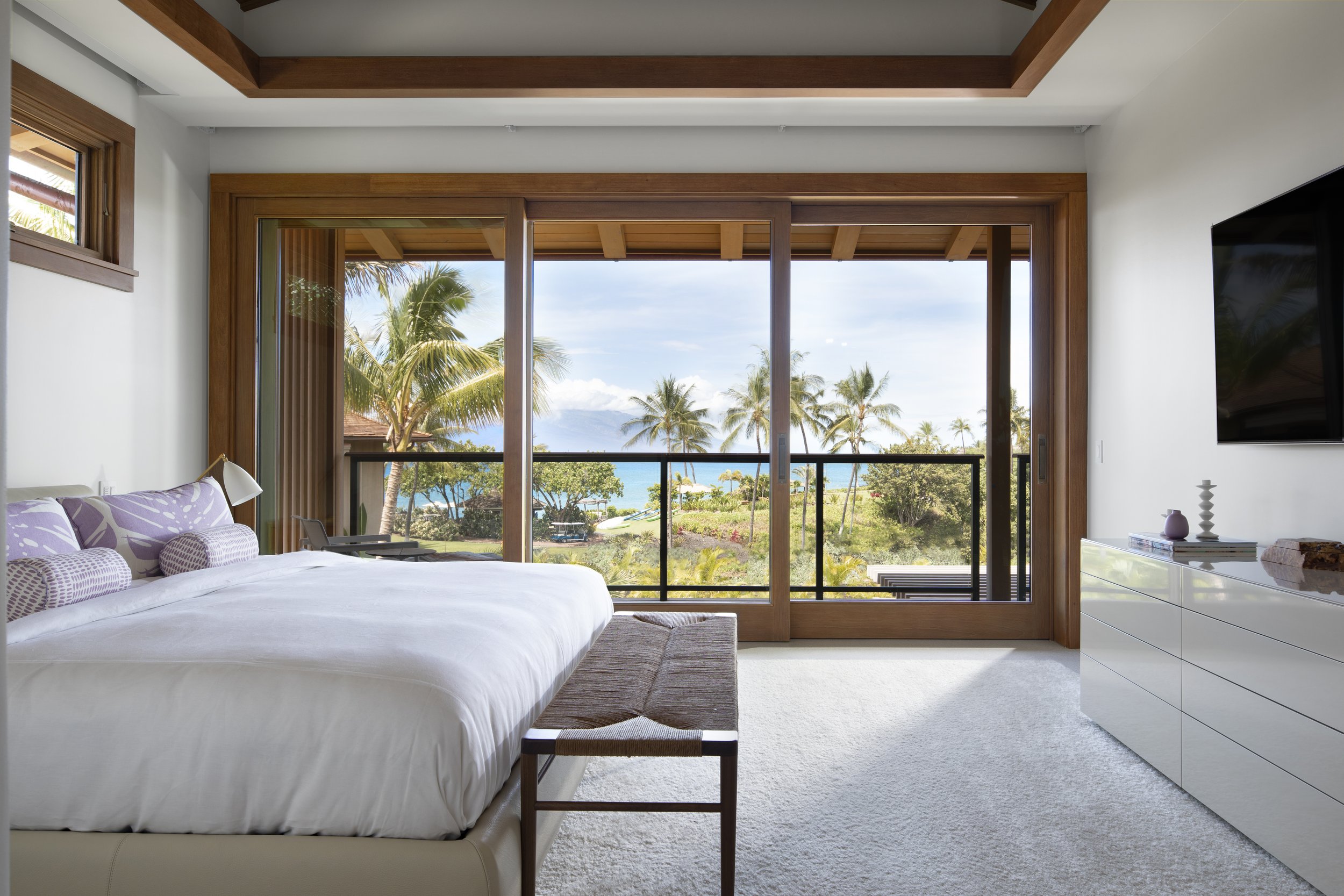 Bedroom with a bench at the foot of the bed and sliding doors to an ocean view balcony