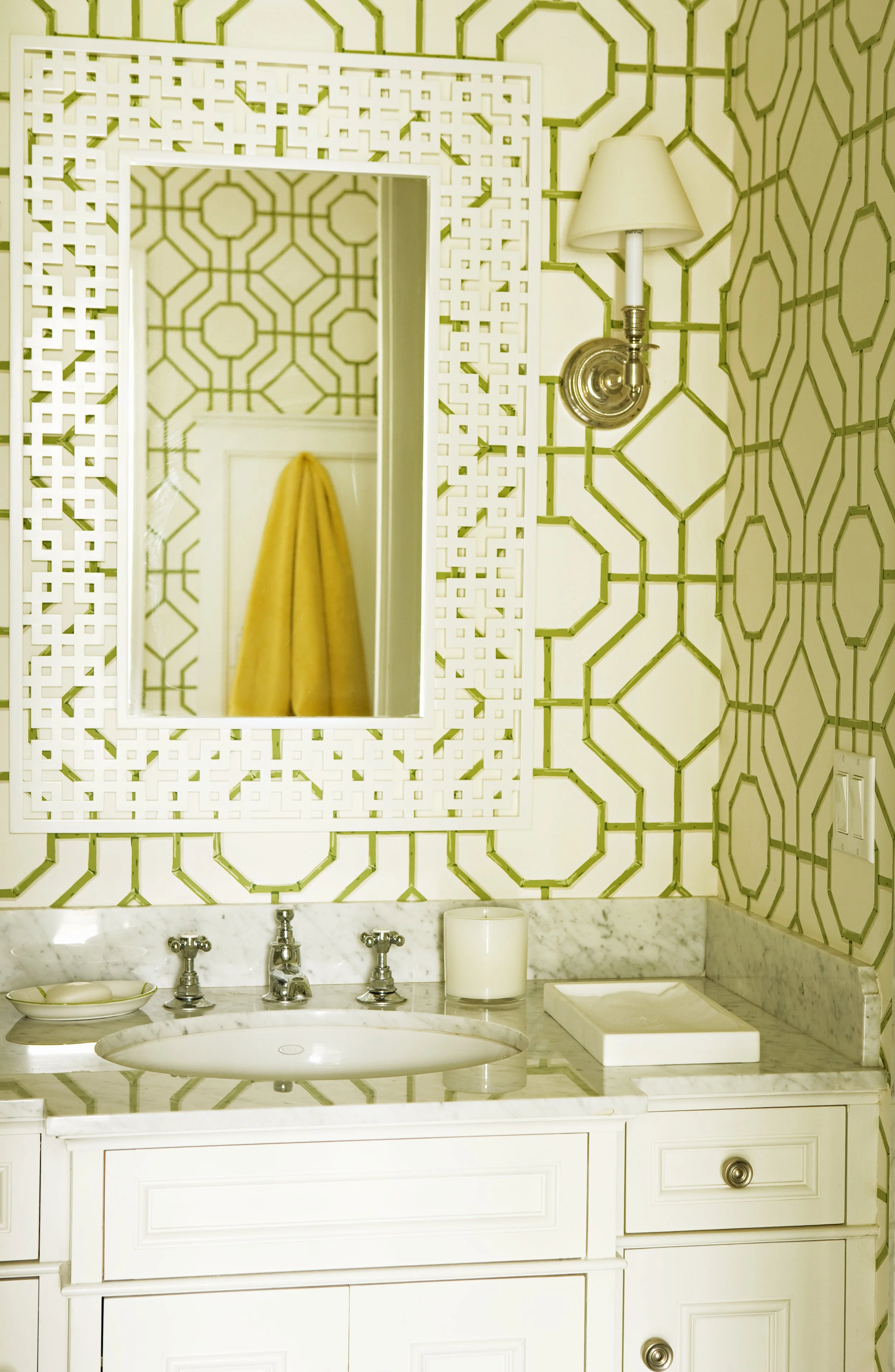 Bath with green and white trellis wallpaper, a lattice mirror and a yellow towel