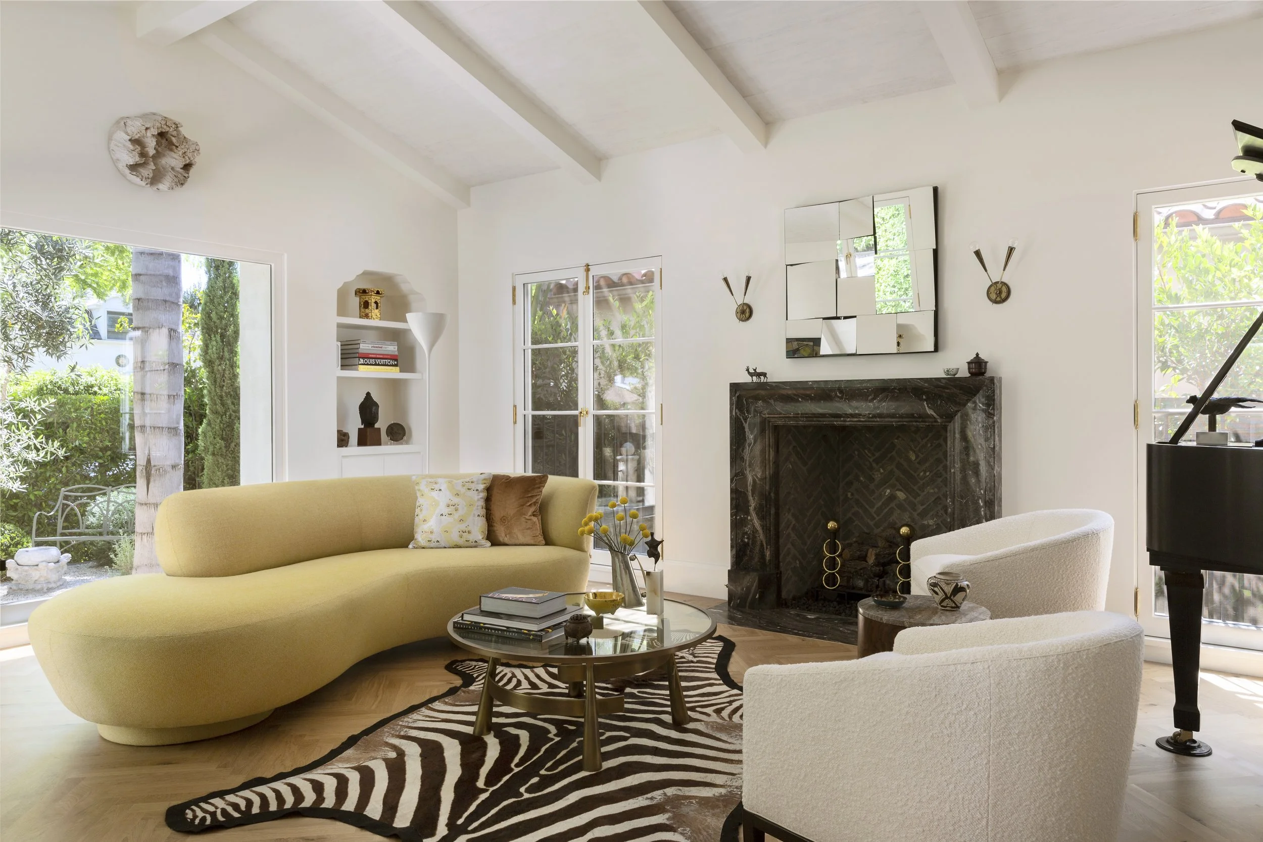 Living room with a curved cream sofa, zebra rug and a dark fireplace