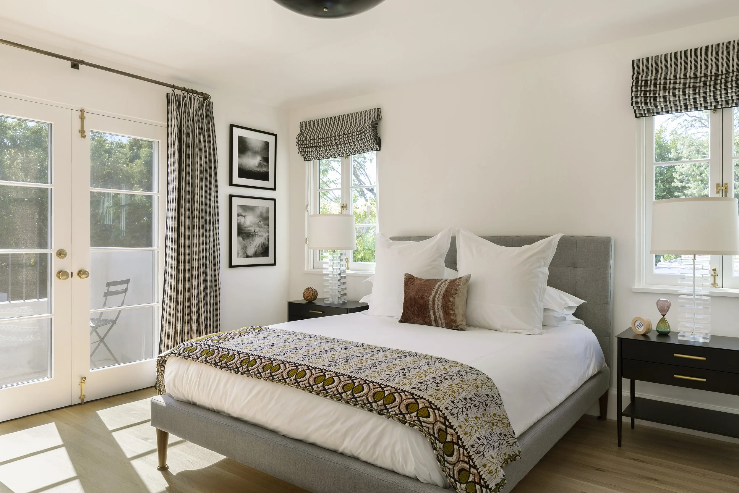 Guest bedroom with a gray upholstered bed, patterned throw and balcony door