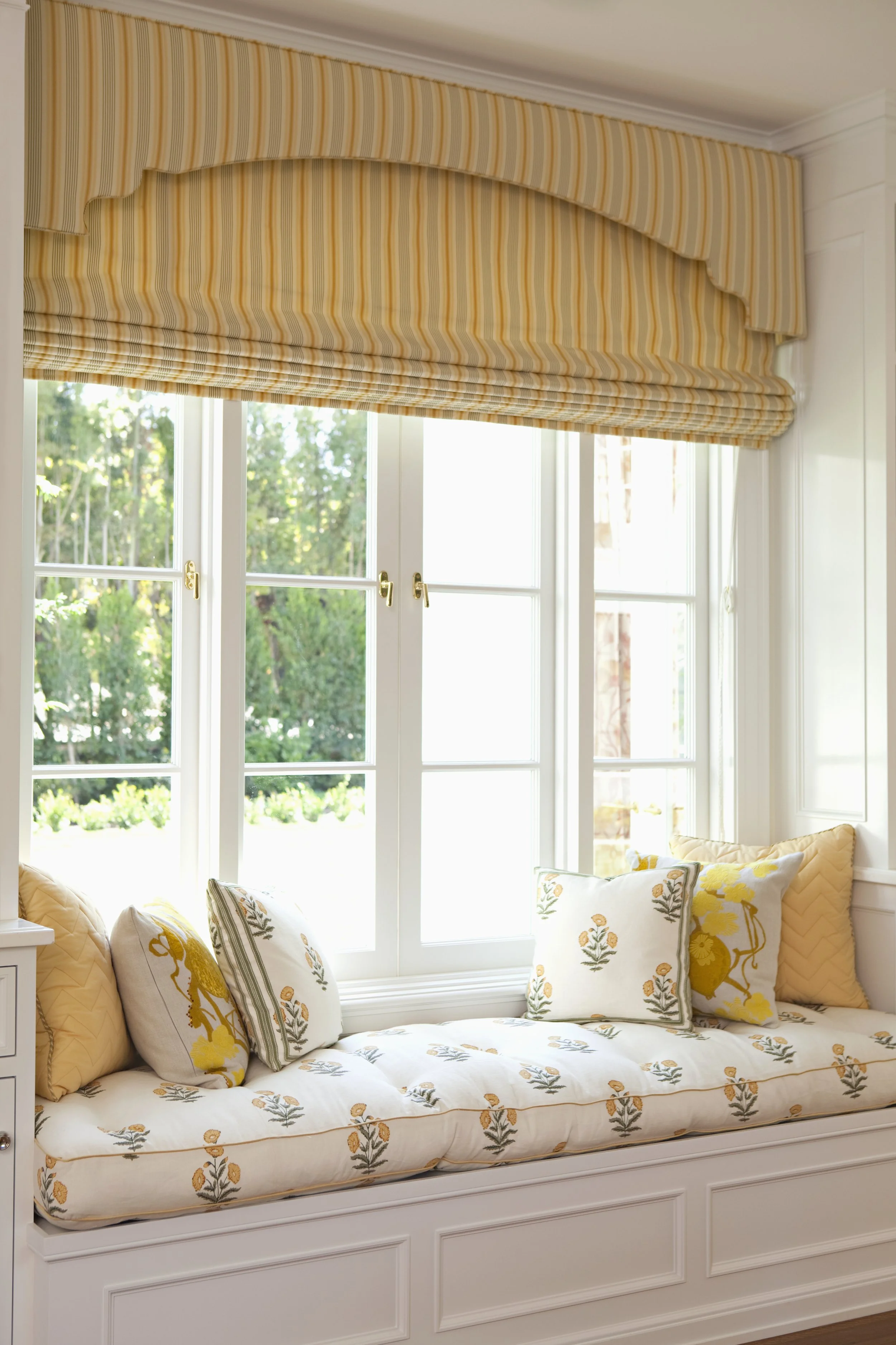 French doors with garden views and a window seat with yellow patterned cushions