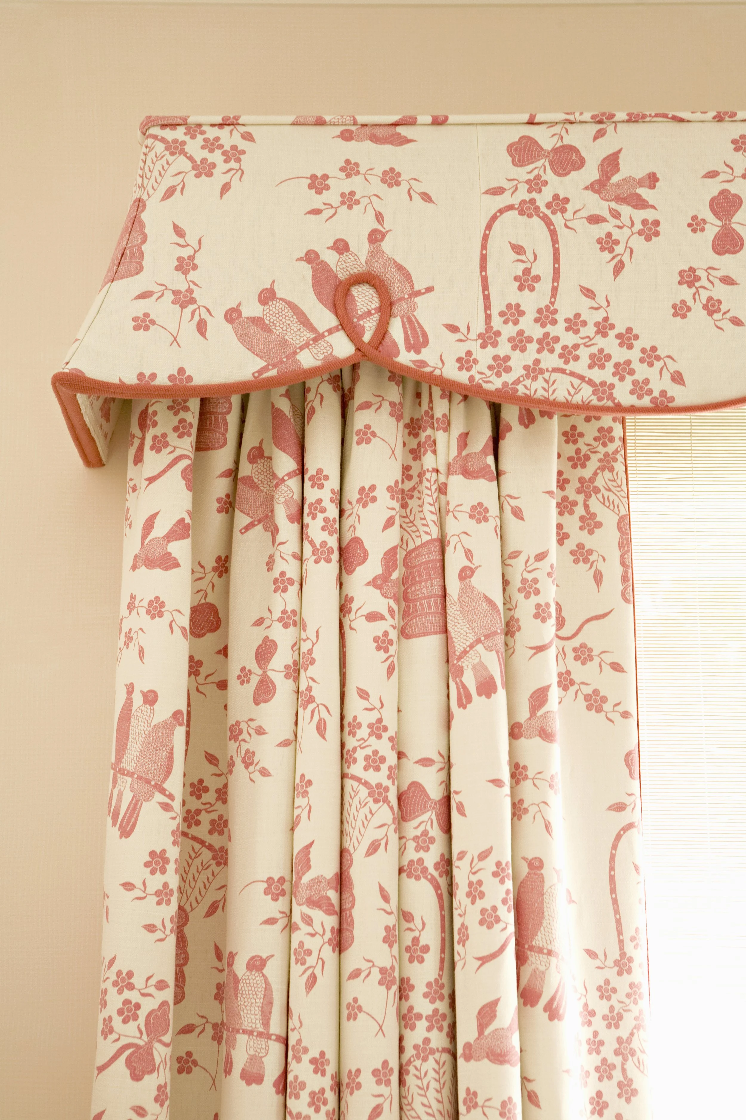 Detail of pink and cream bird print curtains with a scalloped valance