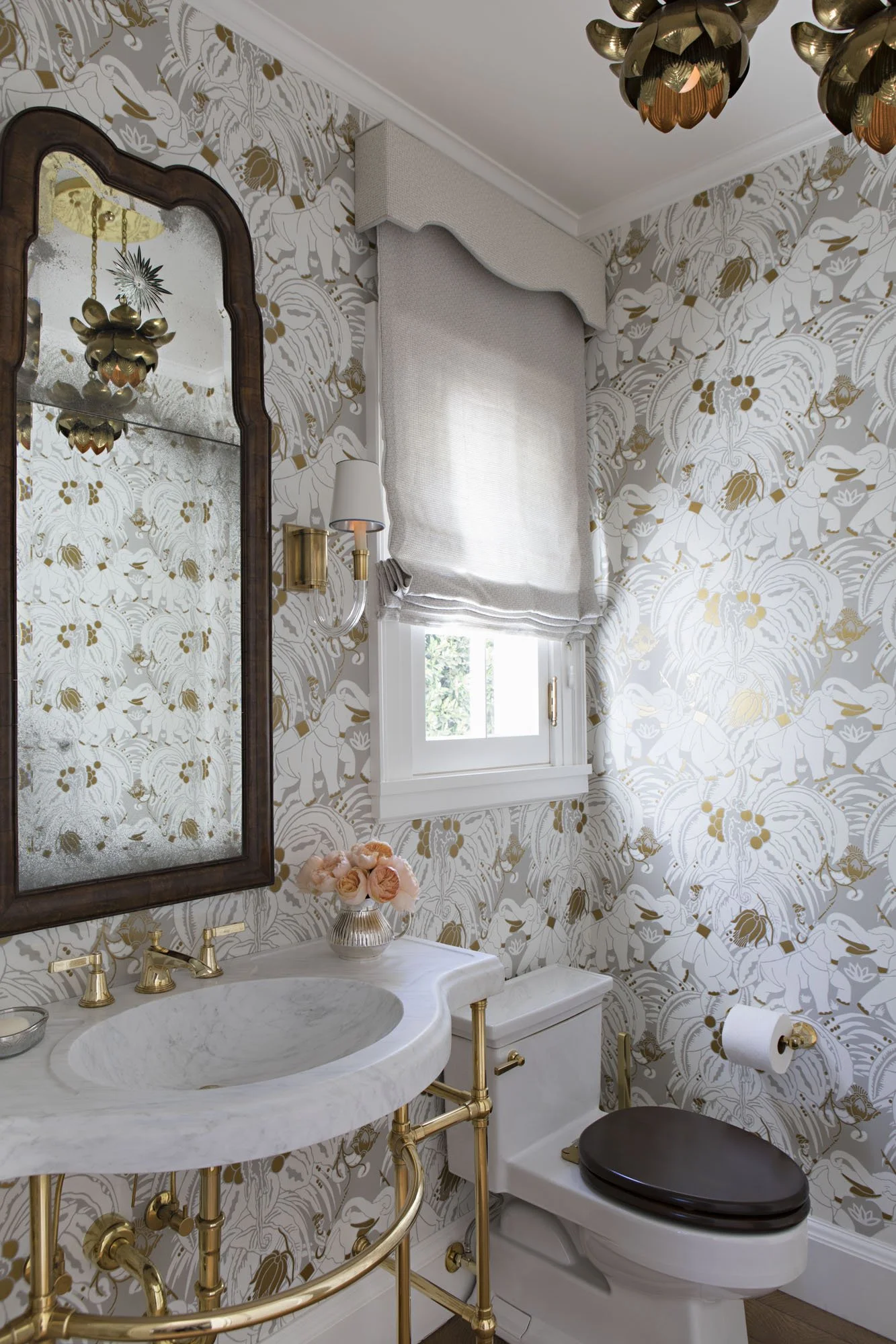 Powder room with gold and white floral wallpaper, mirrored cabinet and marble sink