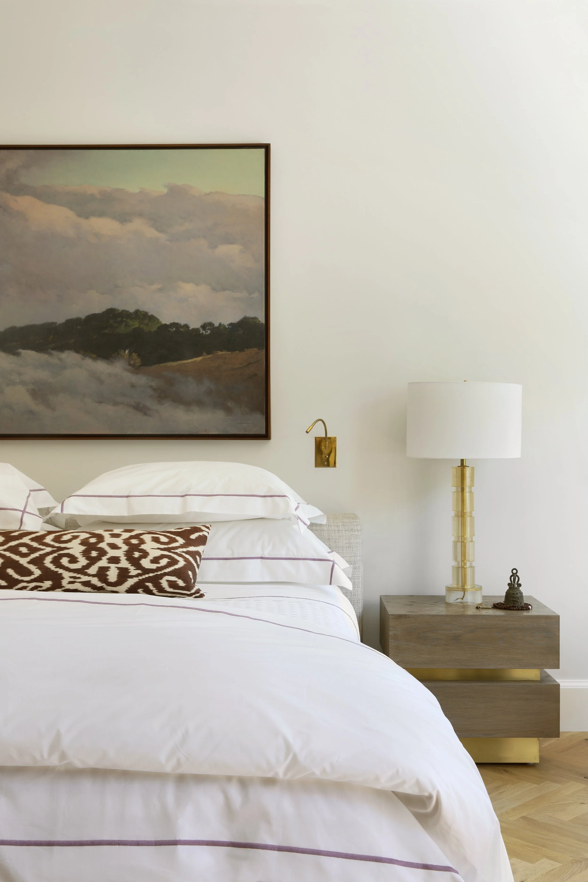 Bedside with a landscape painting, brass lamp and leopard print pillow