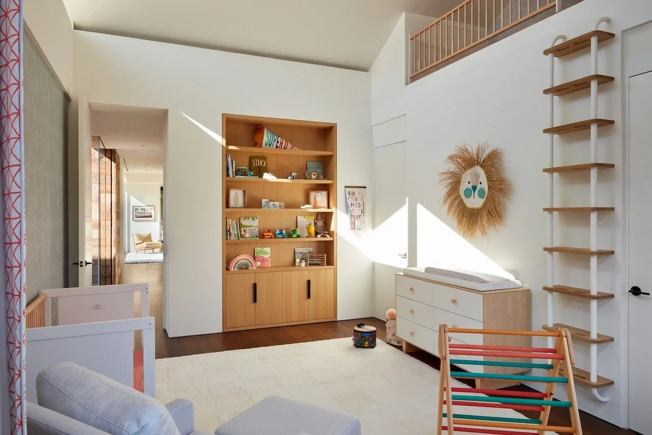 Playroom with built-in oak shelves, a sunburst mirror and a loft railing above