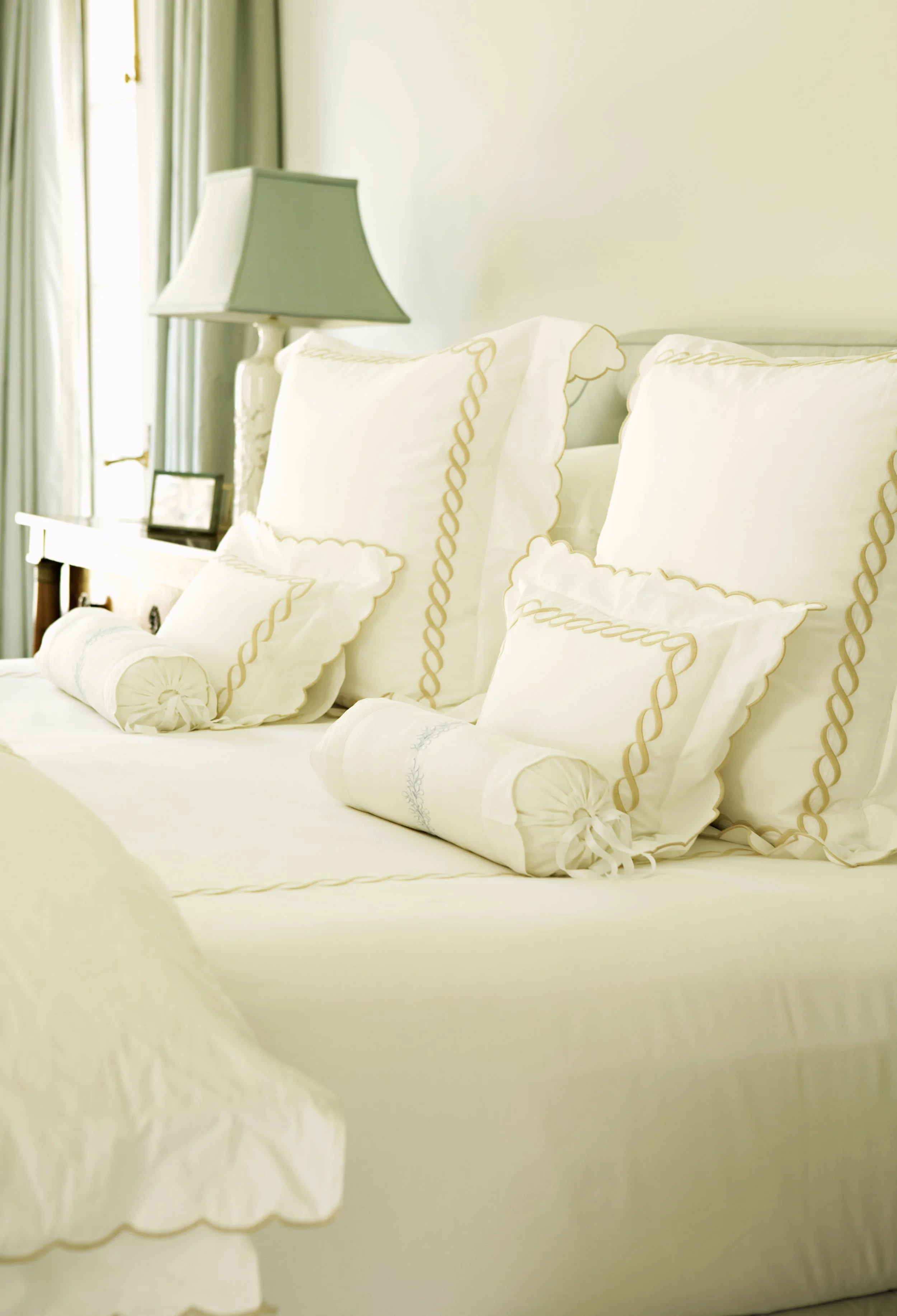 Bed linens with gold rope trim and bolster pillows