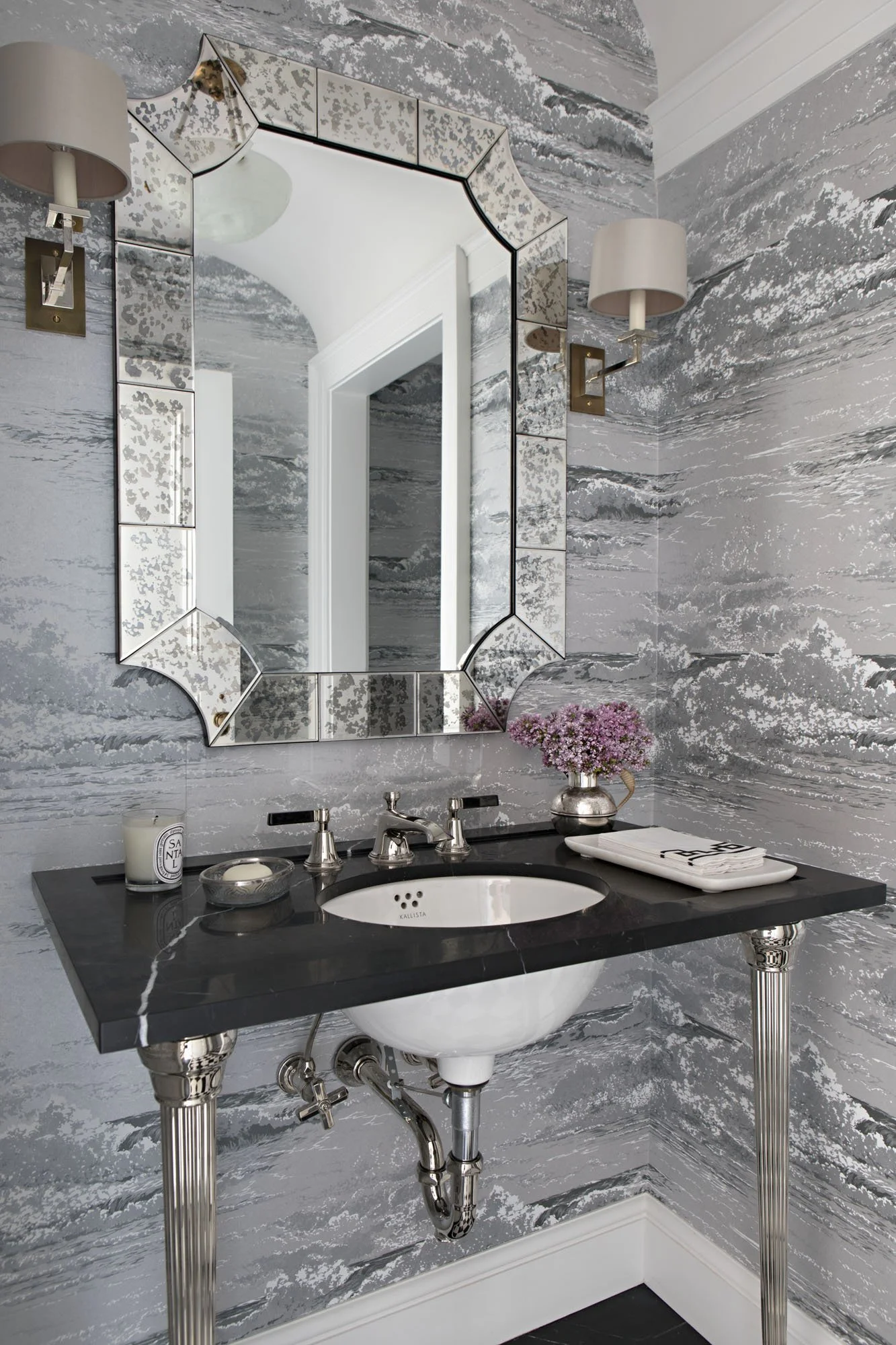 Powder room with gray cloud pattern wallpaper, black marble vanity and antiqued mirror