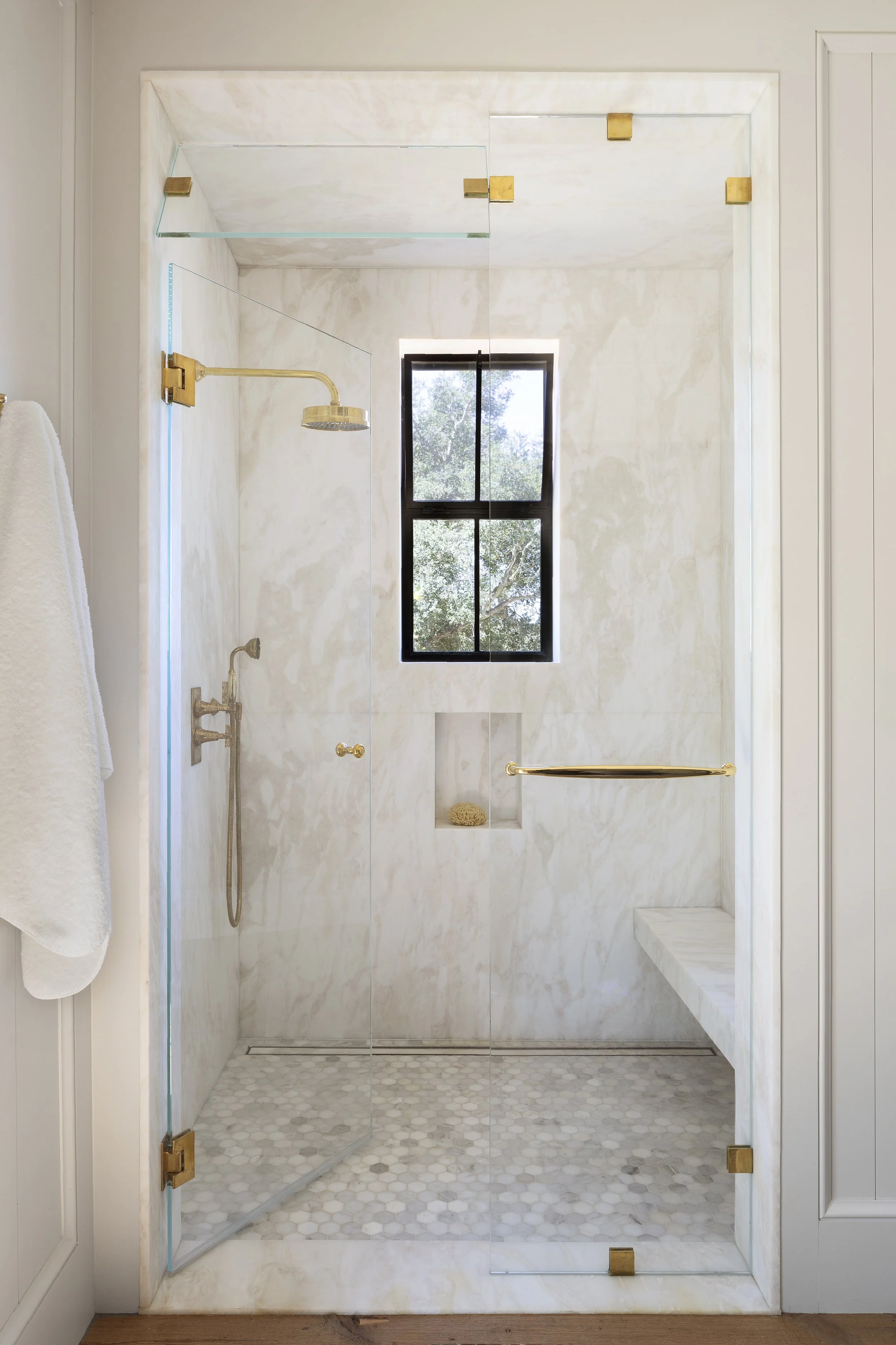 Shower with pale handmade tile, brass fixtures and a built-in niche